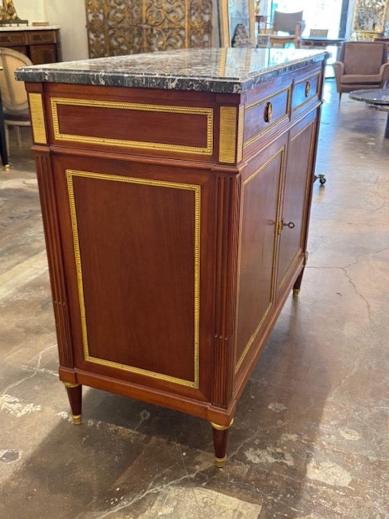 L'armoire en acajou de style Louis XVI avec dessus en marbre du milieu du XXe siècle est un meuble luxueux et élégant qui respire la sophistication. Fabriqué en acajou de haute qualité et doté d'un plateau en marbre, ce meuble témoigne de la