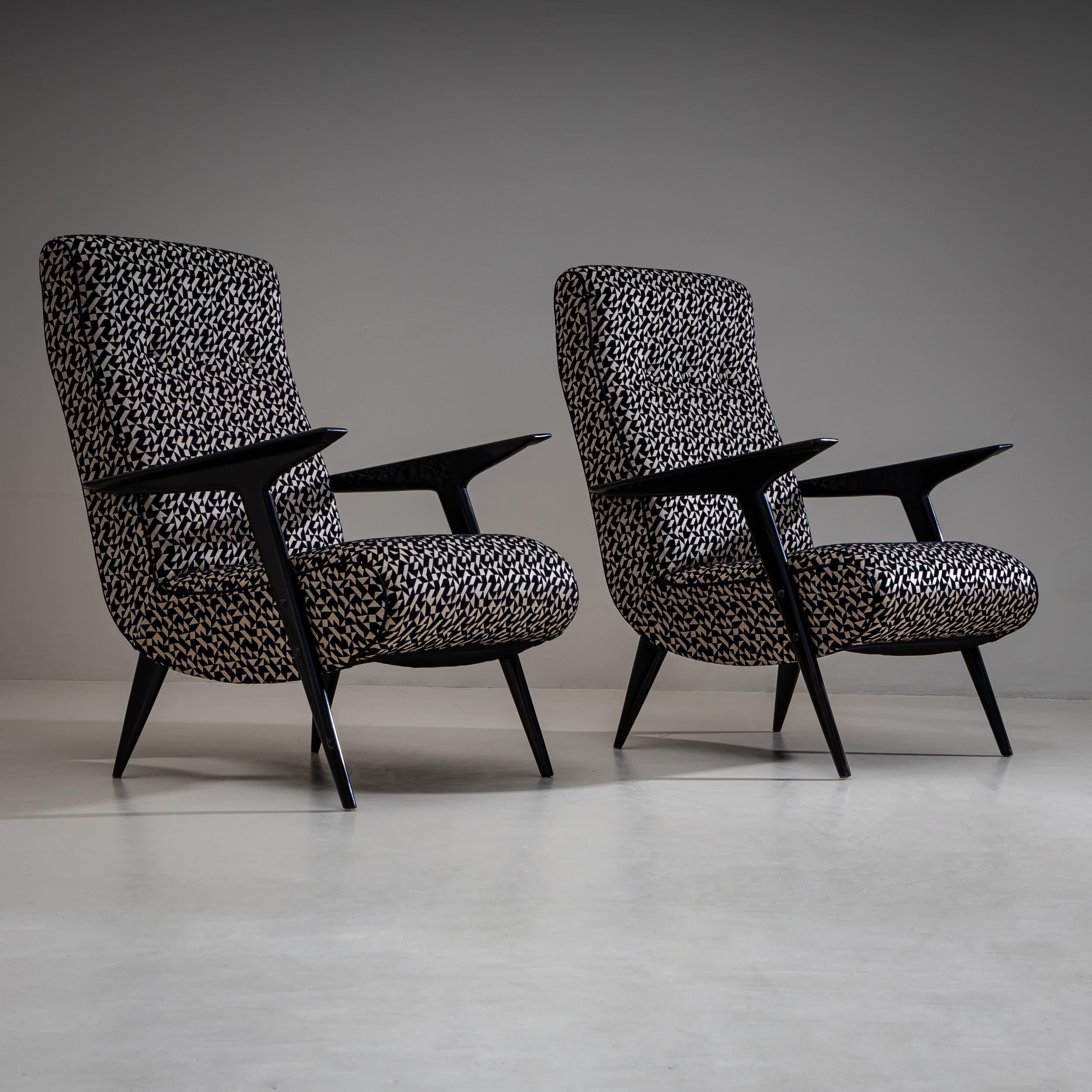 Pair of lounge chairs featuring upholstered seats and backrests. The armrests and legs are black lacquered. The chairs have been newly reupholstered in a black-and-white geometric patterned fabric.