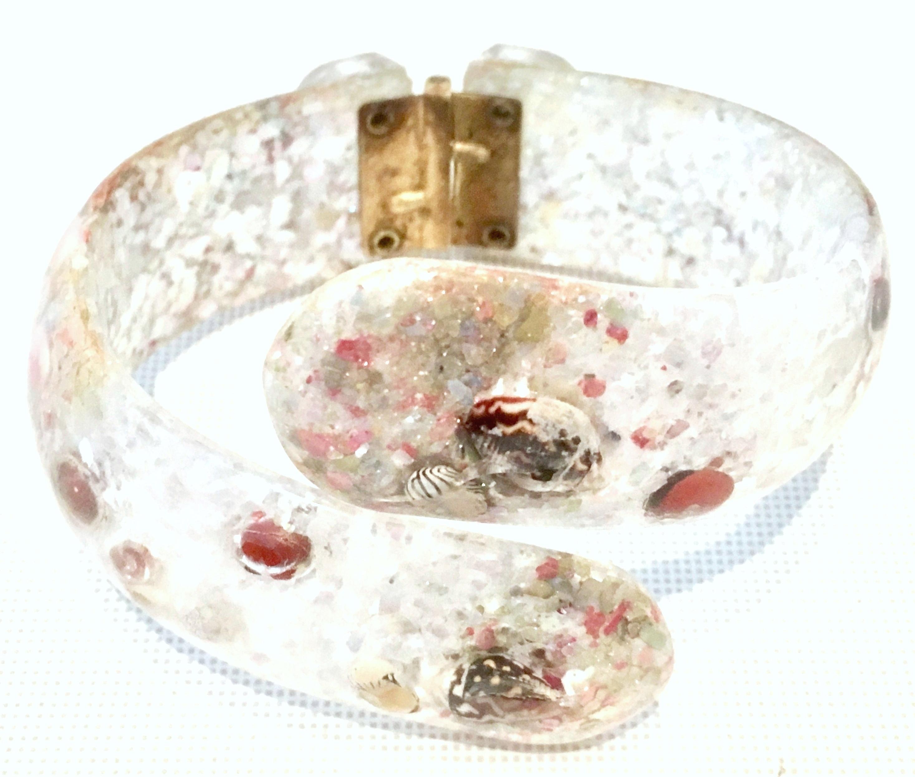Mid-20th Century Lucite & Shell Infused Clamper Bracelet. This unique and rare piece features translucent Lucite infused with both crushed and whole authentic shell. The hinge is gilt brass.
Interior diameter is, 2