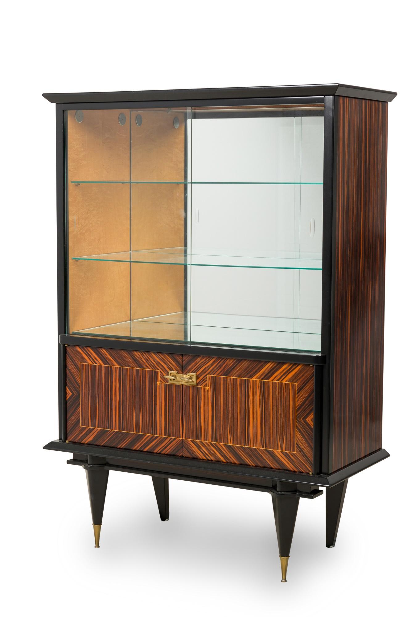 Step into the glamour of the mid-20th century with this extraordinary Macassar Ebony Wood Vitrine Cabinet, showcasing the iconic Art Deco style. Imbued with clean lines and geometric precision, this piece is a masterpiece of design, blending form