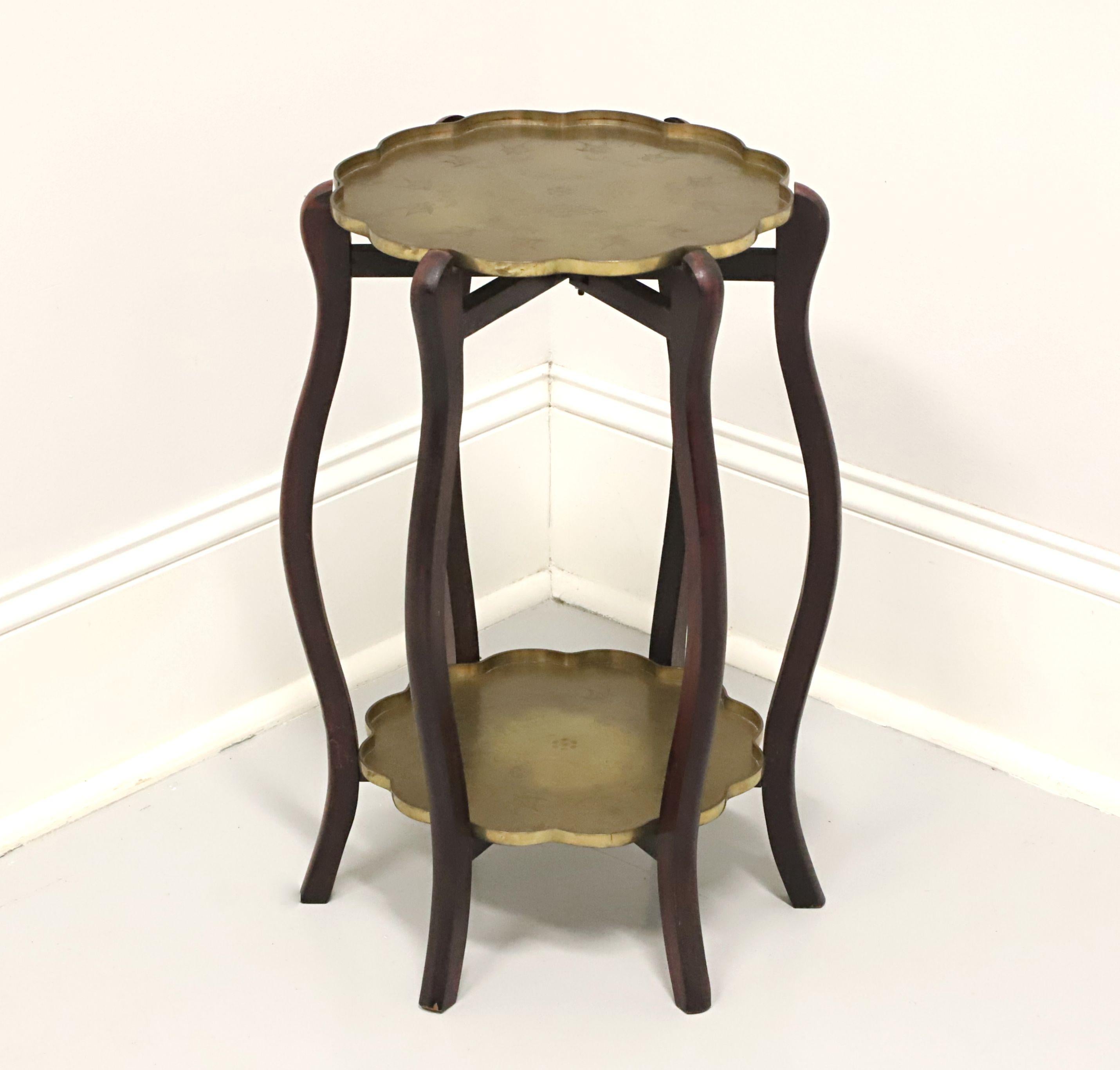 An Asian style collapsible tray table with brass trays, unbranded. Mahogany with an open design of six curved legs supporting an upper tier for a larger brass tray over a lower tier for a slightly smaller brass tray. Brass trays have Chinoiserie