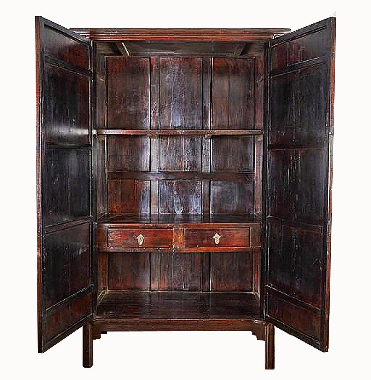 A tall mahogany cabinet, circa 1900, from China. Deep red stained, two drawers, top and bottom shelves, corner legs and original bronze hardware. Very good condition. 
