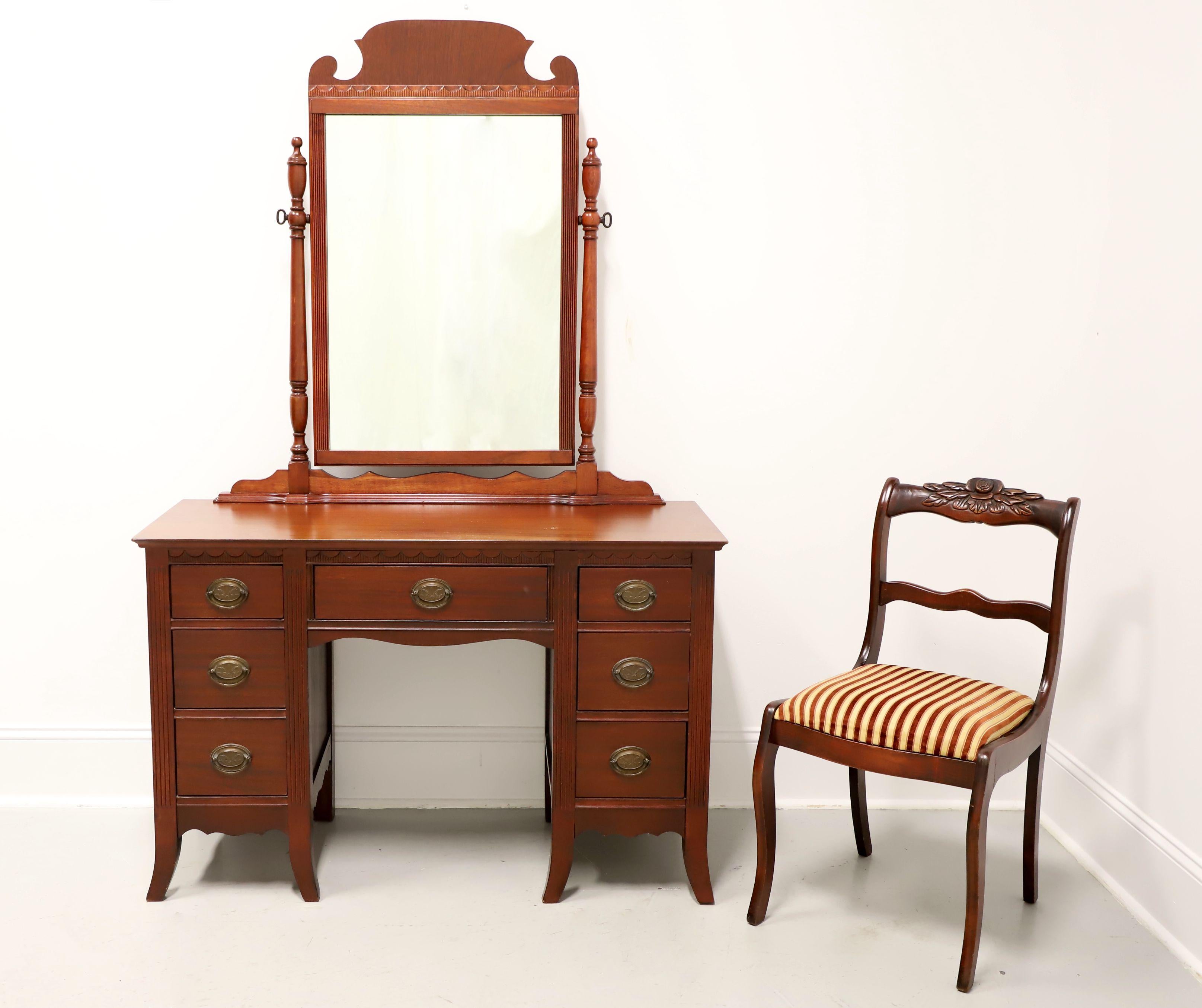 A Hepplewhite style three-piece vanity set, unbranded. Vanity is mahogany with brass hardware, a miter edge to the top, decorative carvings above the drawers, carved apron, and flared front legs. Features center kneehole and seven drawers of