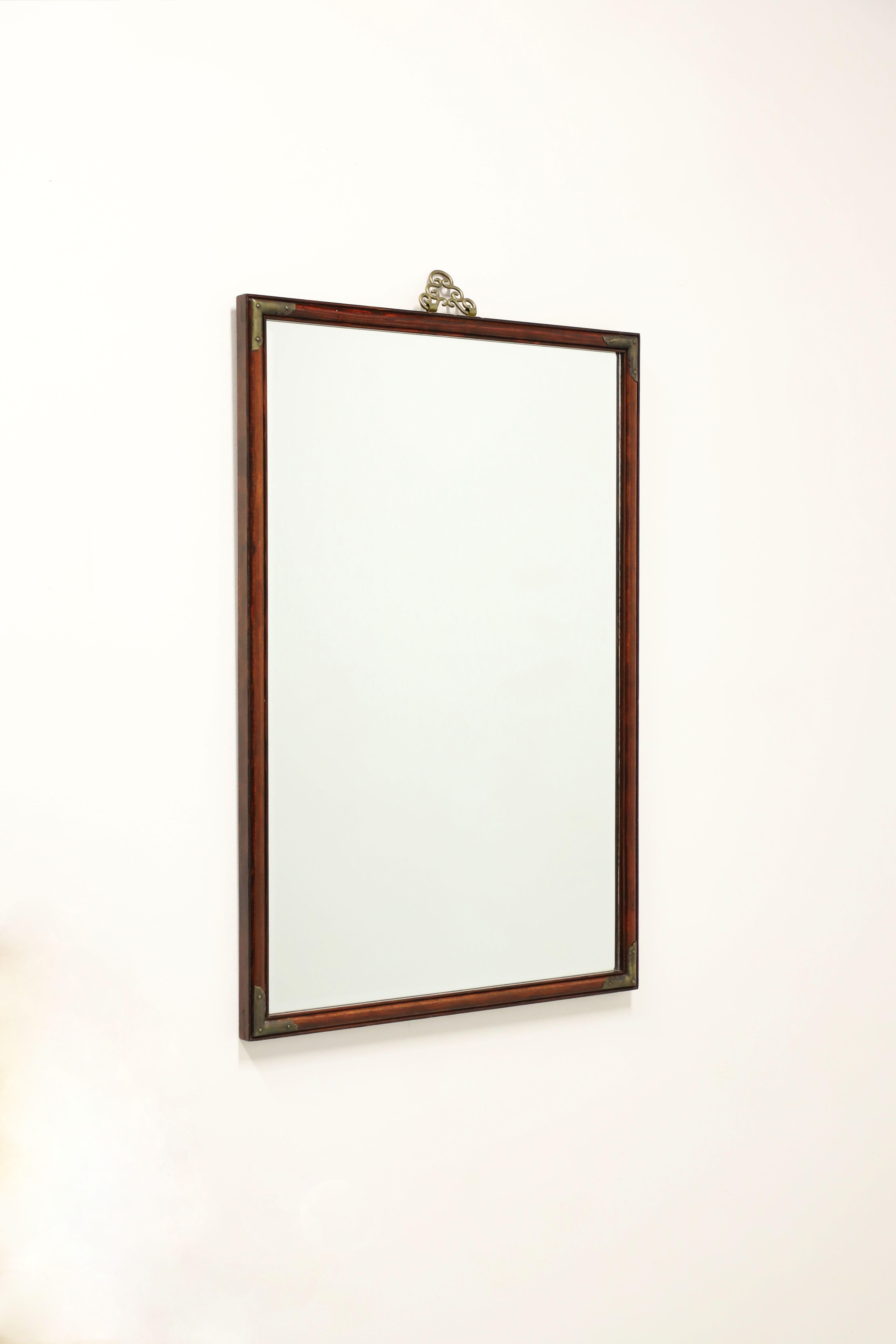 A Japanese Tansu Campaign style wall mirror, unbranded, similar quality to Henredon. Beveled mirror glass in a rectangular mahogany frame with decorative Japanese Tansu brass accents and hanger. Likely made in North Carolina, USA, in the mid 20th