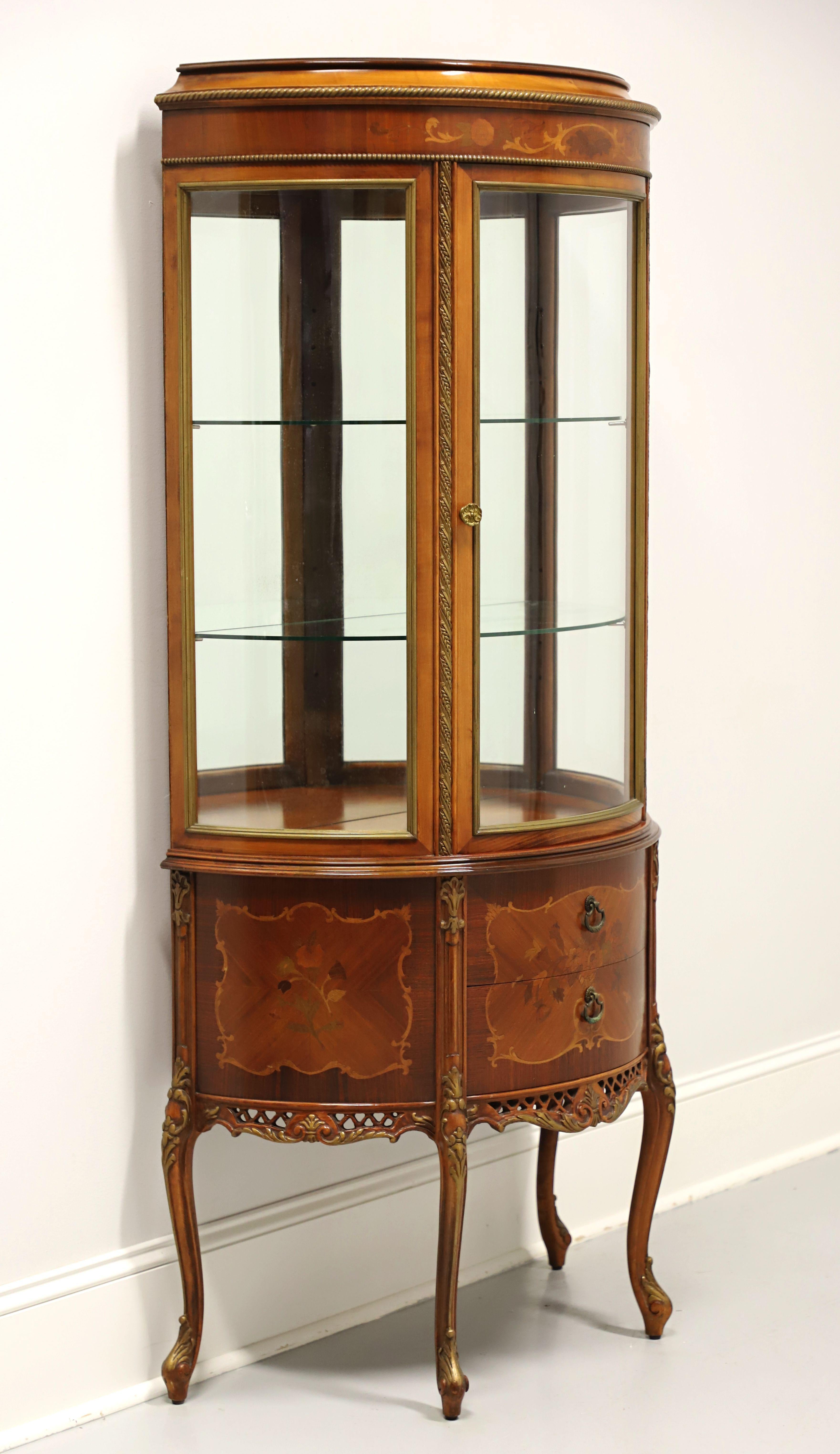 A French Louis XV style display vitrine, unbranded. Mahogany & satinwood with floral marquetry designs, half-circle in shape, brass hardware, decorative gold painted accents, open carved apron, and elevated on gold accented curved legs with pad