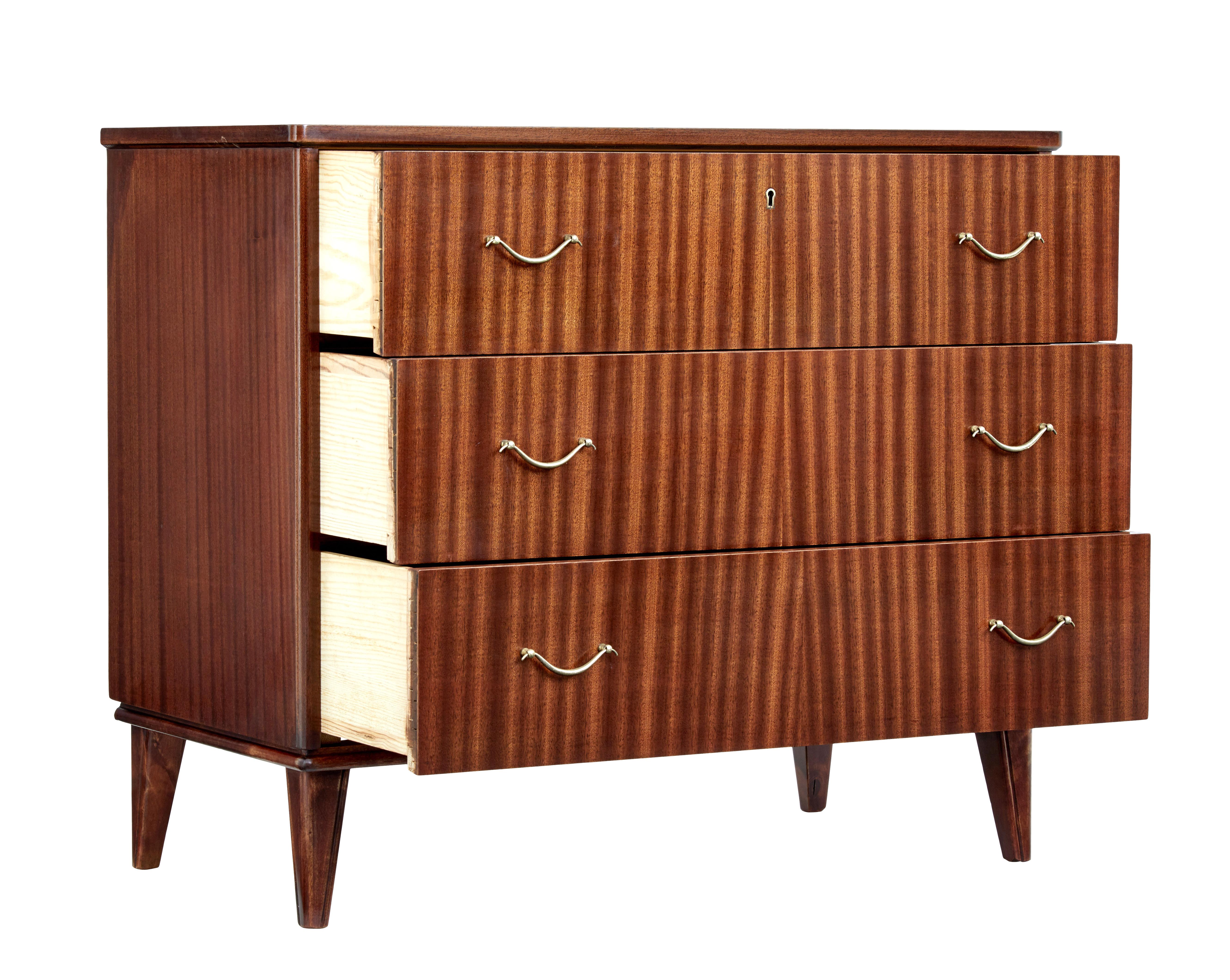 Mid-20th century mahogany Scandinavian chest of drawers, circa 1960.

Good quality piece of Scandinavian design. 3 drawers of equal size fitted with brass handles. Rich golden color. Standing on tapered legs.

Area of restoration to veneer loss