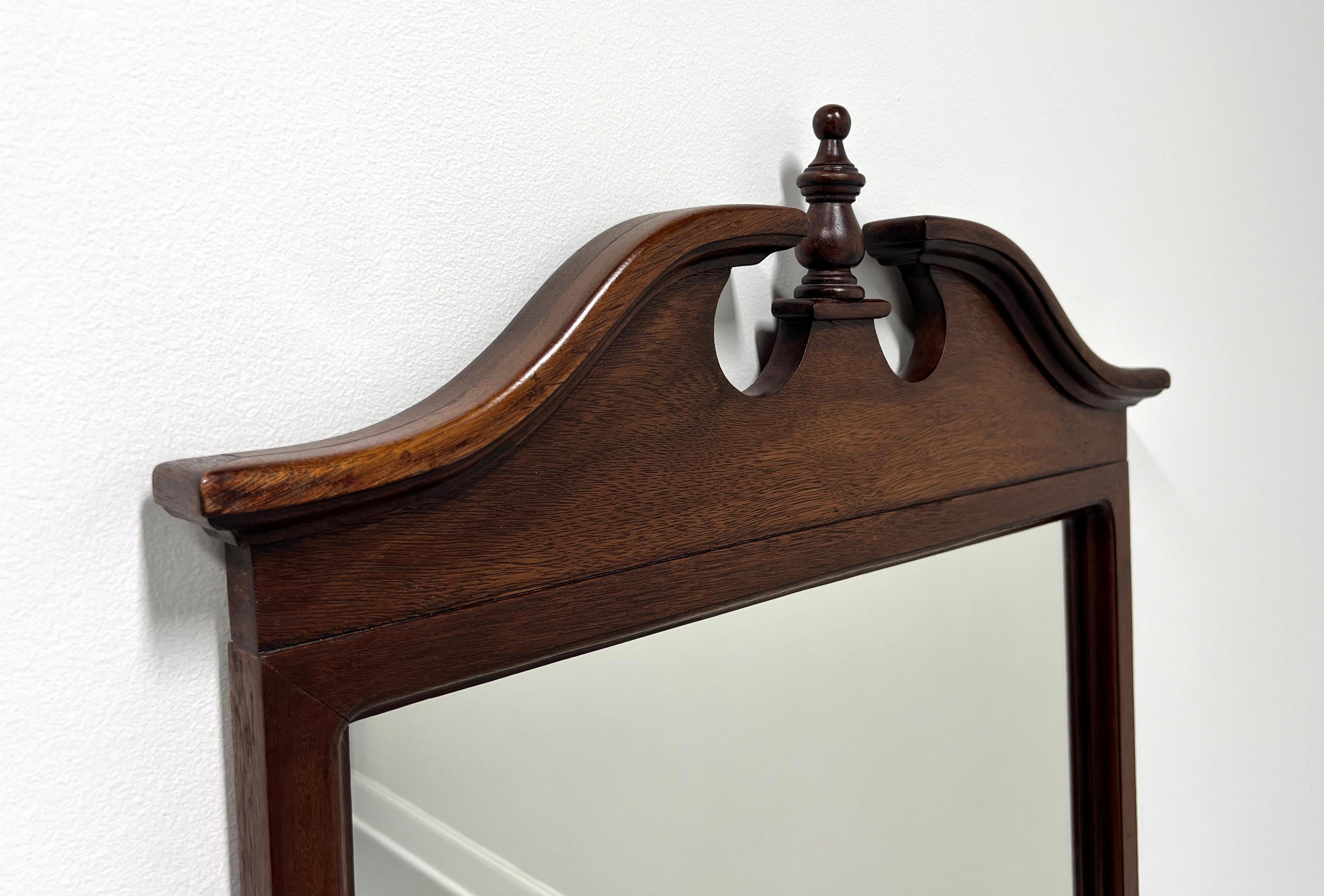 A Traditional Federal style wall mirror, unbranded, similar quality to Drexel or Lexington. Mirrored glass, mahogany frame with pediment and center finial to top. Made in the USA, in the mid 20th Century.

Measures:  24.75w 1.75d 45.5h, Weighs