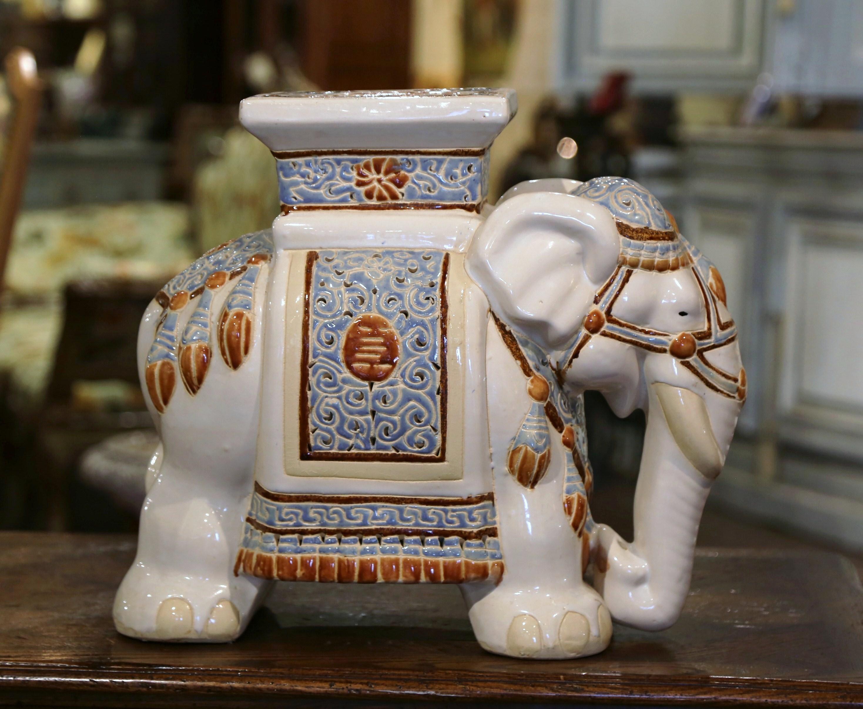 Crafted in Malaysia circa 1960, the ceramic seating is in the shape of an elephant, and heavily decorated in oriental finery. The mammal has a rectangular seat at the top, and is hand painted in the rust, white and pale blue palette. This unique