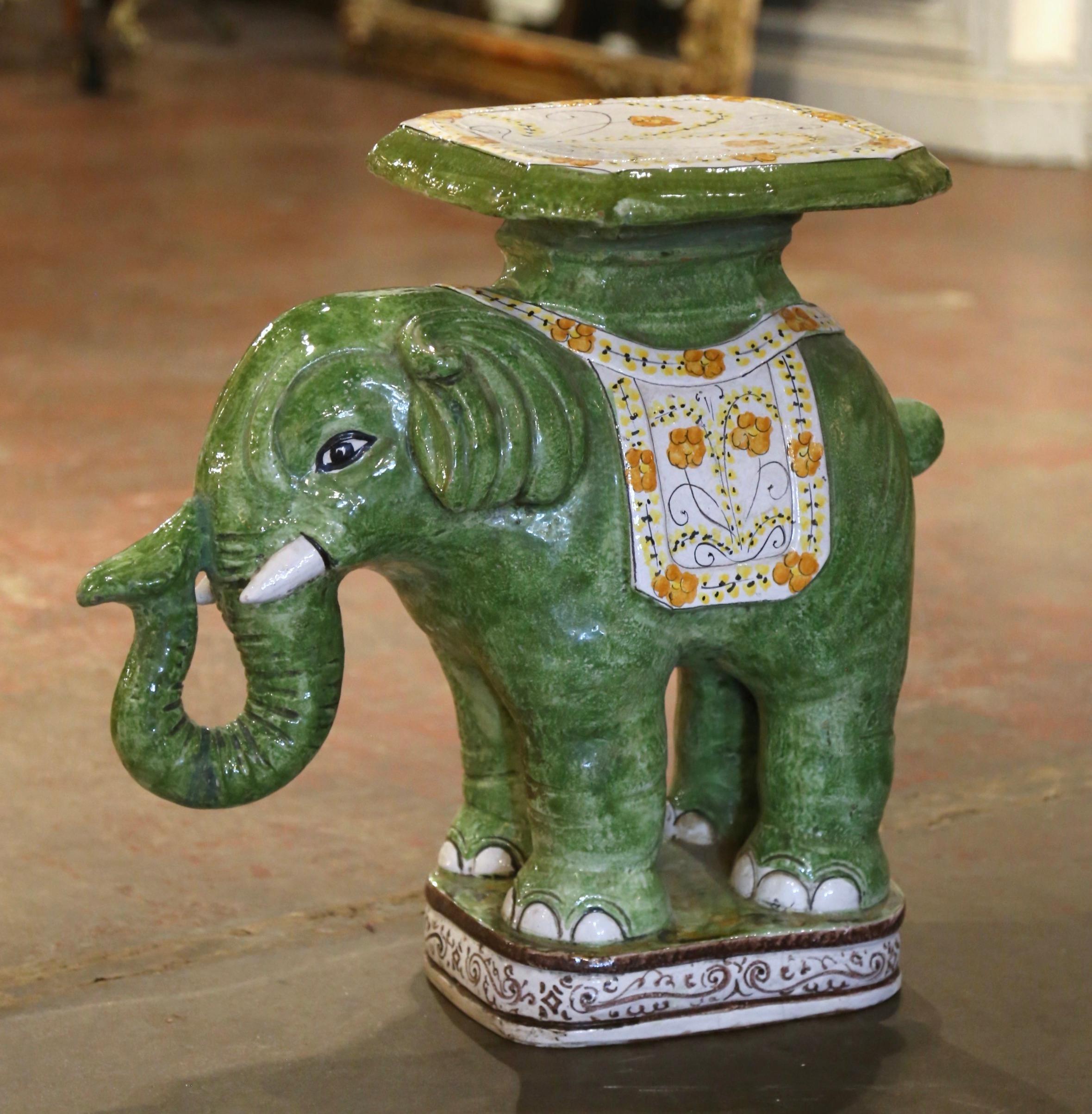 Crafted in Malaysia circa 1960, the large ceramic elephant-shape seating is a vibrant piece of mid-century decorative art. Crafted from green ceramic, it features a finely detailed elephant adorned with intricate yellow and white hand-painted