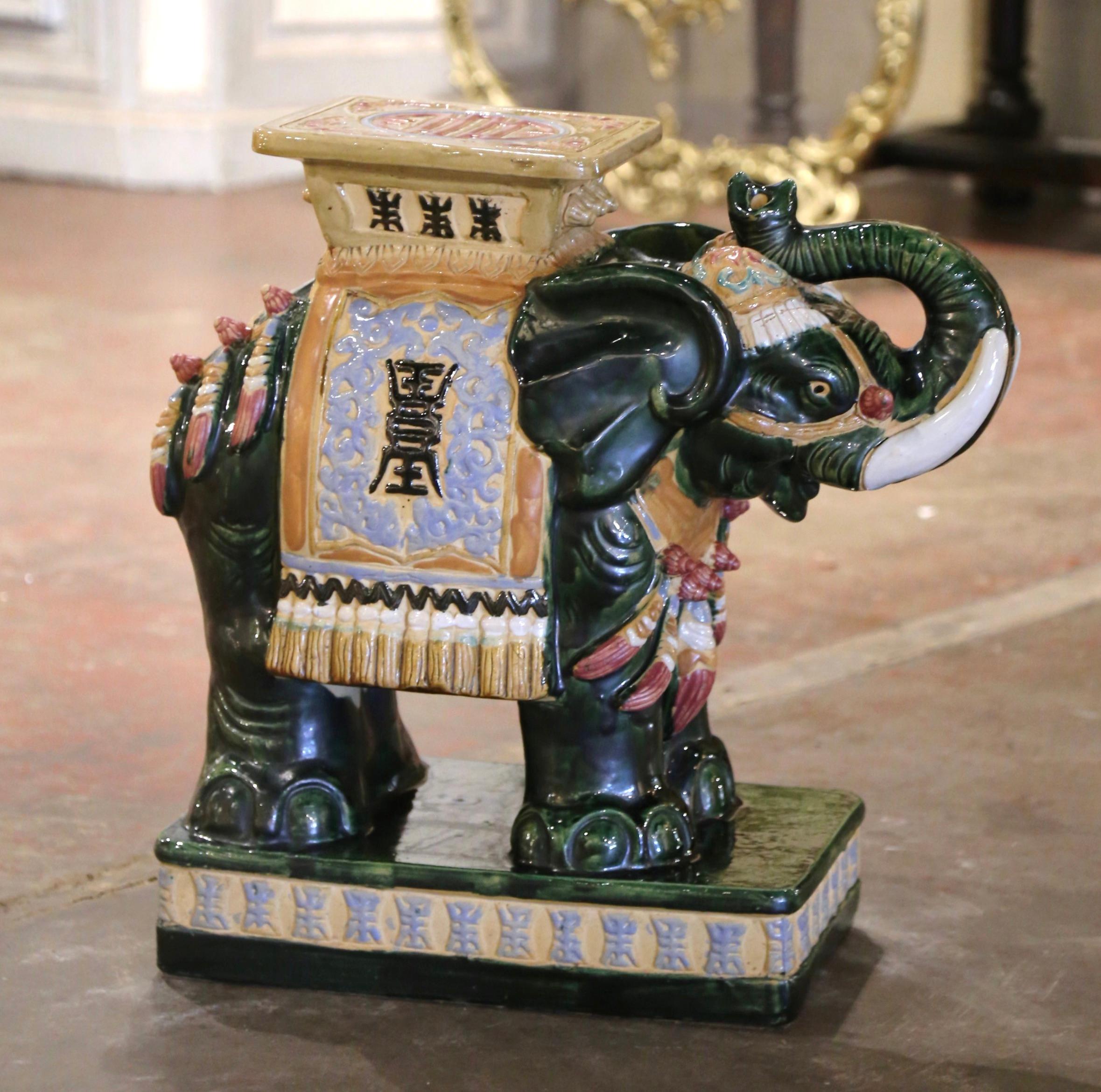 Fabriquée en Malaisie vers 1960, cette grande assise en forme d'éléphant en céramique est une pièce vibrante de l'art décoratif du milieu du siècle. Fabriquée en céramique verte, elle représente un éléphant finement détaillé, orné de motifs