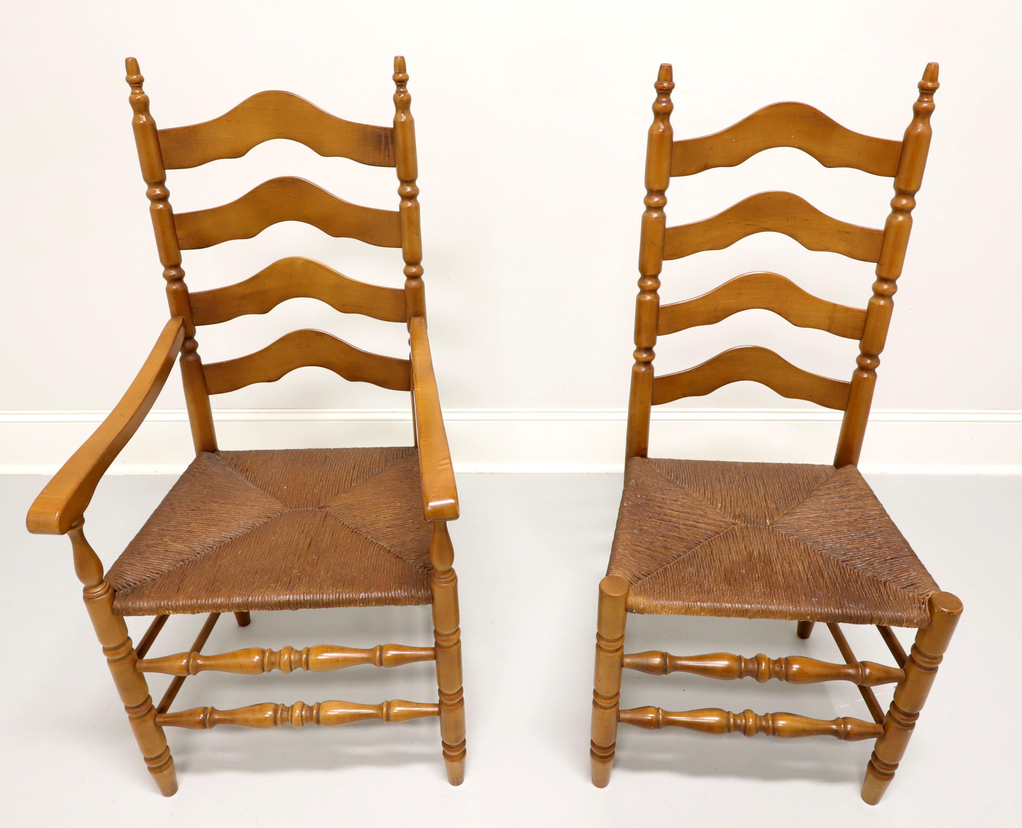 A pair of Cottage / Farmhouse style dining chairs, one armchair and one side chair, unbranded, similar in quality to Ethan Allen. Maple with carved arched ladder back design, curved arms with turned supports to armchair, rush seats, turned front