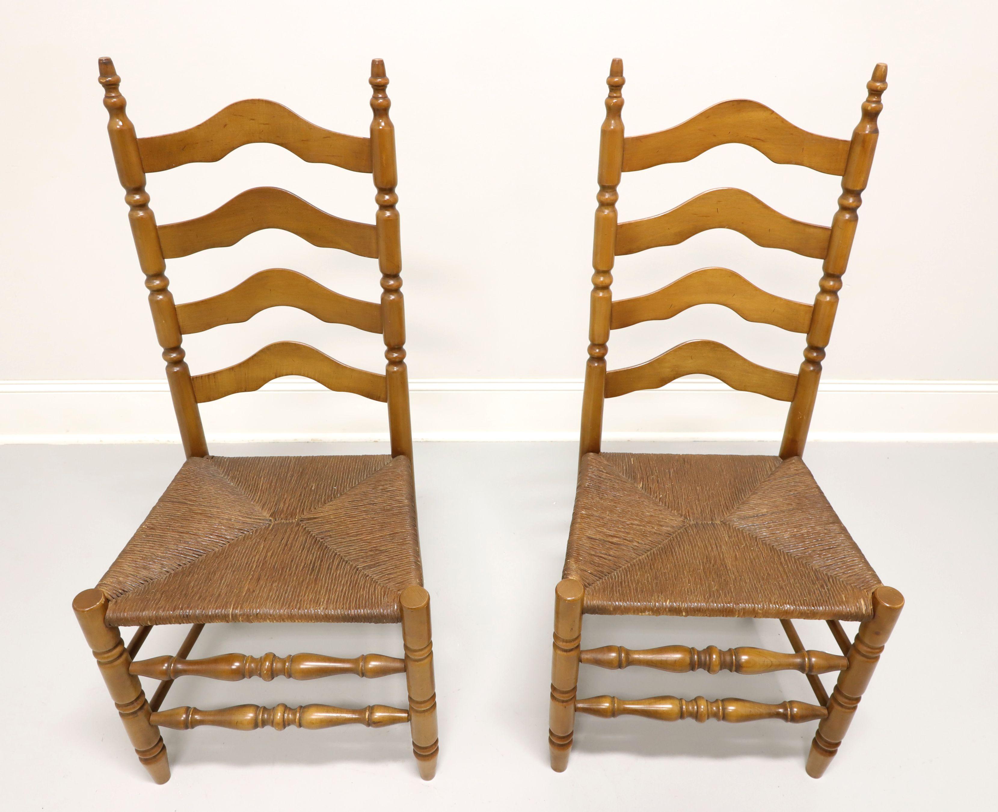 A pair of Cottage / Farmhouse style dining side chairs, unbranded, similar in quality to Ethan Allen. Maple with carved arched ladder back design, rush seats, turned front legs & front stretchers, and solid back legs & back/side stretchers. Made in