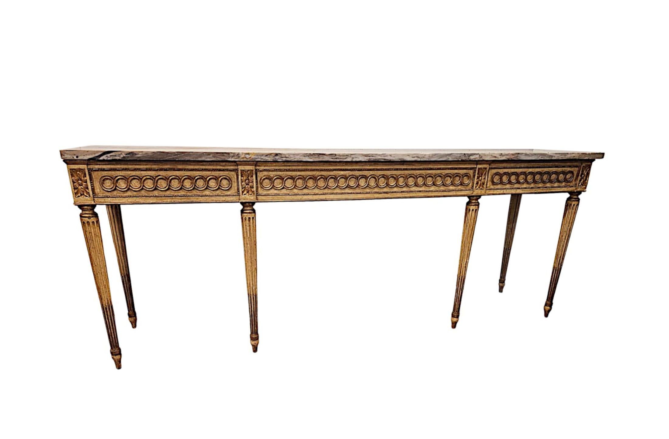Fabuleuse console à plateau de marbre peint et doré du milieu du XXe siècle, finement sculptée, d'une qualité exceptionnelle et aux proportions très longues et étroites.  Le remarquable plateau de marbre de Calcutta moulé, de couleur crème et or, de