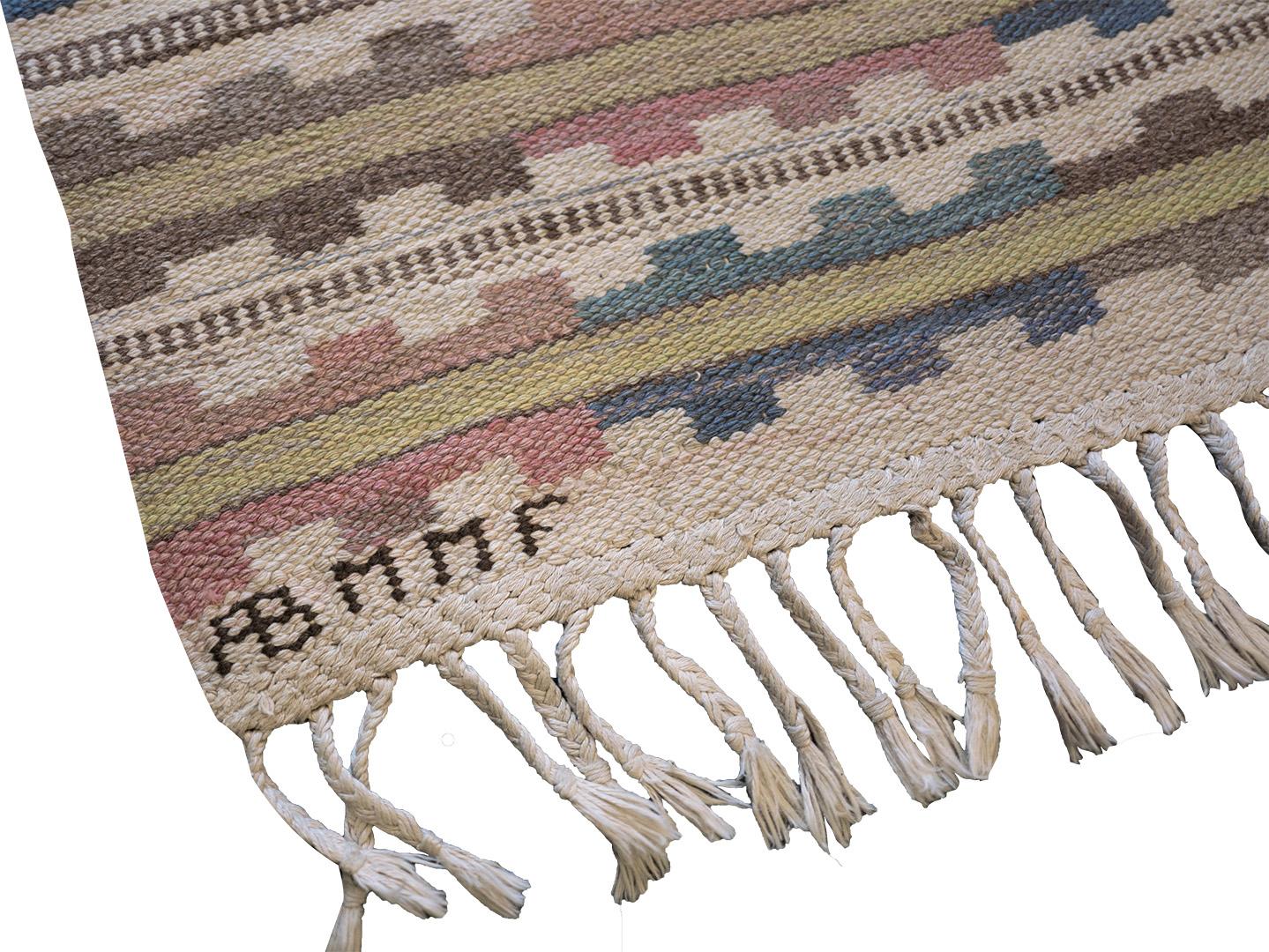 Dieses 1933 von der schwedischen Textildesignerin Märta Måås-Fjetterström entworfene, traditionelle, handgewebte schwedische Flachgewebe hat ein elfenbeinfarbenes, gestreiftes Feld mit einem polychromen, gezackten Paneelmuster in einer verspielten,