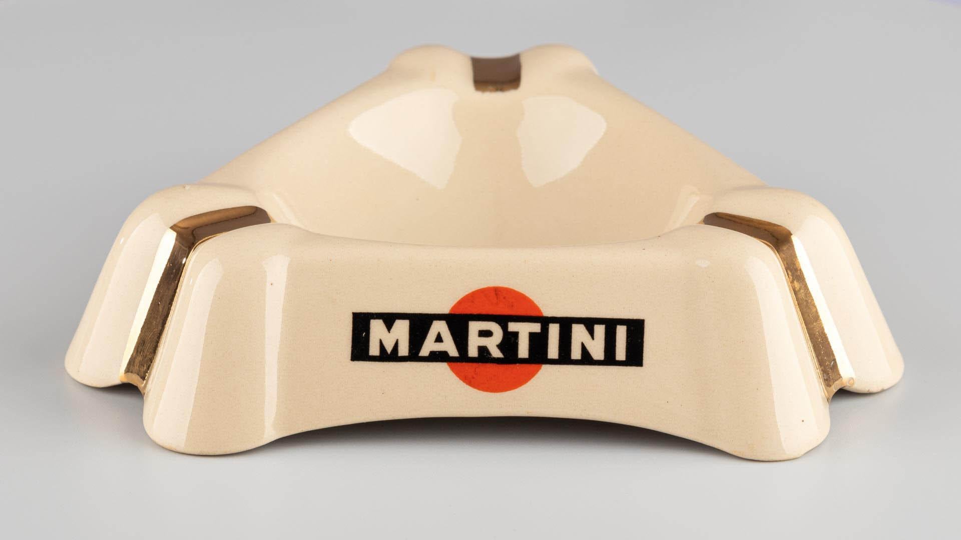 Cendrier Martini

France
Céramique émaillée
vers 1950-1970

Dimensions :
H × L : 4 × 16 cm

Description :
Ce cendrier trilobé est un exemple de céramique promotionnelle du milieu du XXe siècle conçue pour l'industrie hôtelière. Chaque lobe comporte