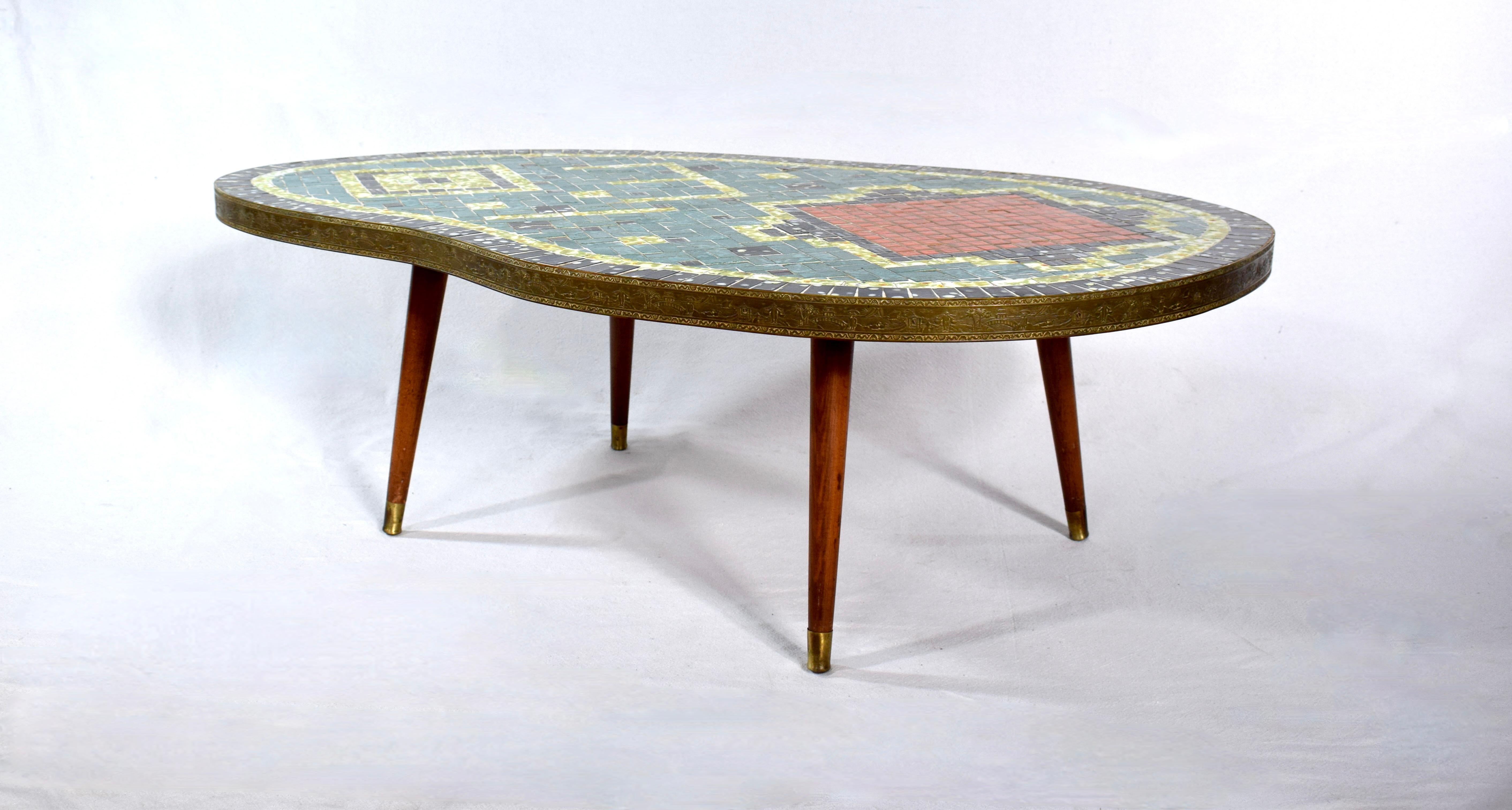 Mid century biomorphic mosaic tile table.  Biomorphic kidney shape with abstract green, orange, black & yellow tiles & brass surround. Tapered splayed brass capped legs are removable.