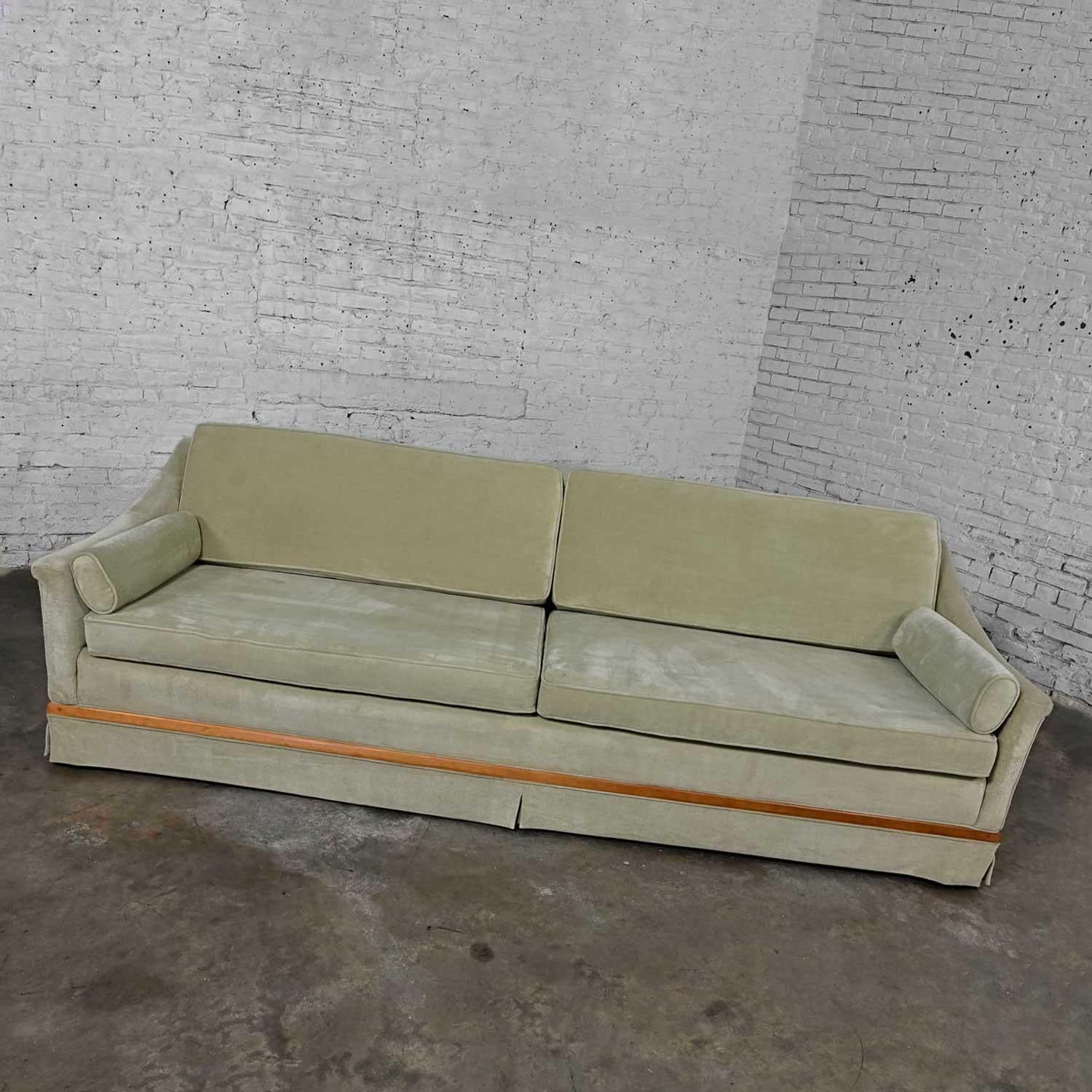 Lovely vintage MCM (a.k.a. Mid-Century Modern) green velvet sloped arm sofa with oval arm bolster pillows, walnut trim, and turned, round tapered walnut finished wood legs. Beautiful condition, keeping in mind that this is vintage and not new so
