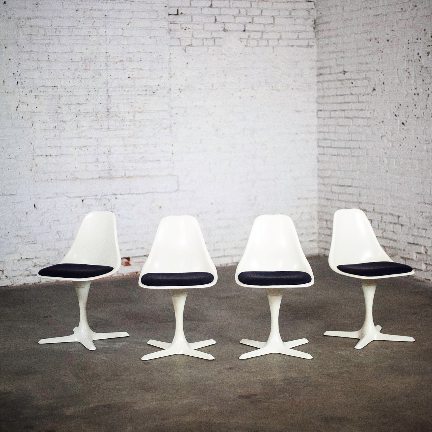 Wonderful Mid-20th Century Mid Century Modern Tulip chairs by Burke comprised of white fiberglass armless shells or frames & 4 prong fiberglass bases, white painted metal shafts, & black hopsacking fabric on the seat cushions, set of 4. Beautiful