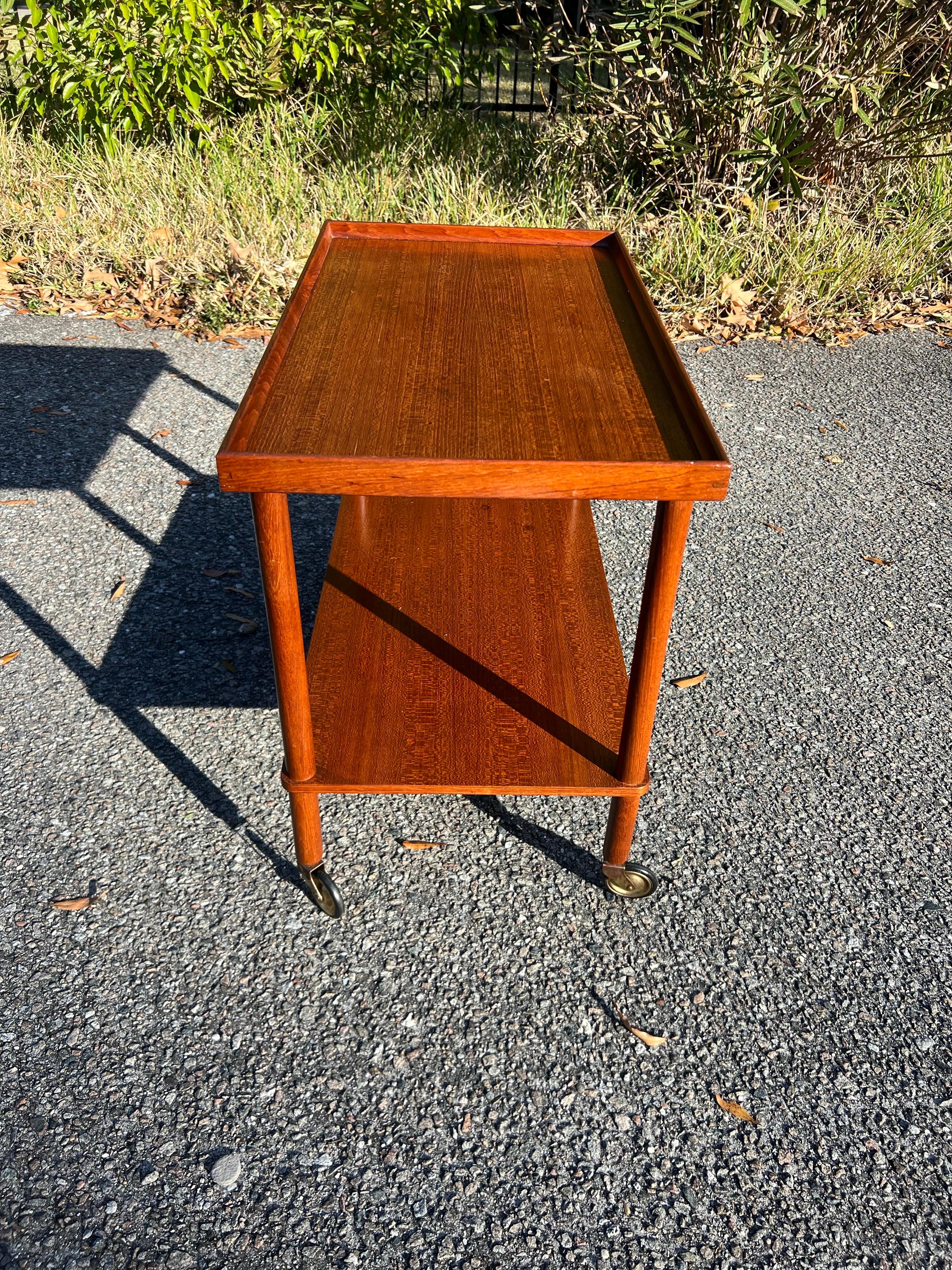 Joints à queue d'aronde apparents. Incroyables roues vintage avec des capuchons en laiton. Magnifique grain de teck. Bord surélevé au niveau supérieur pour empêcher les boissons, les verres et les cocktails de glisser. 

Cette pièce est parfaite et