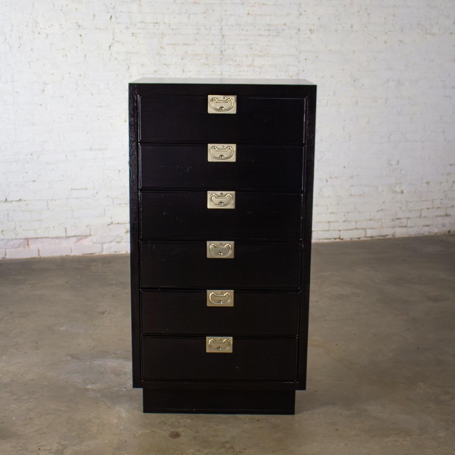 Marvelous vintage Modern Campaign or Hollywood Regency black lacquered narrow chest of drawers or lingerie cabinet with recessed base & brass hardware and an original slightly distressed finish. Beautiful condition, keeping in mind that this is