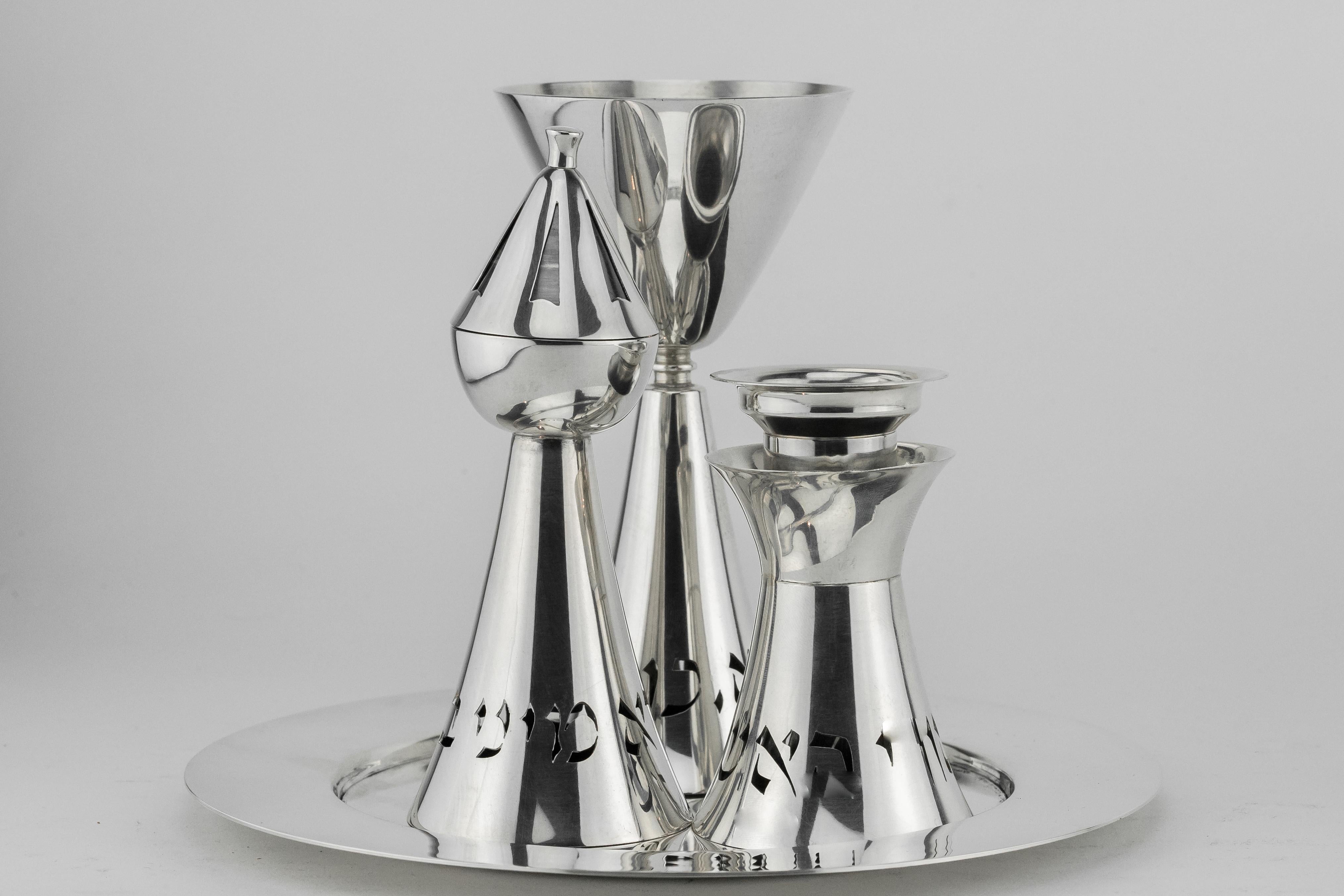 Modern sterling silver Havdalah set, Ludwig Wolpert, Jerusalem, Israel, circa 1955.
Comprising a Kiddush goblet, candleholder, spice tower, all pierced with Hebrew text, on circular tray.
The pierced inscriptions are the Havdalah blessings for wine,