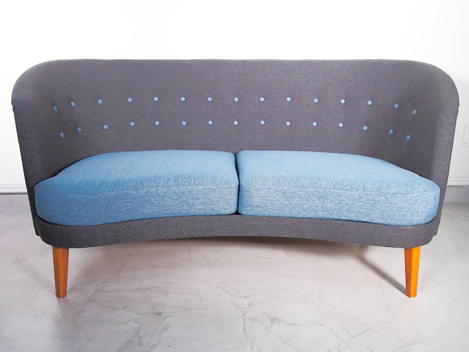 Slightly curved sofa with blue fabric seat upholstery and with a button-tufted grey back. Stained wood legs, later upholstery.