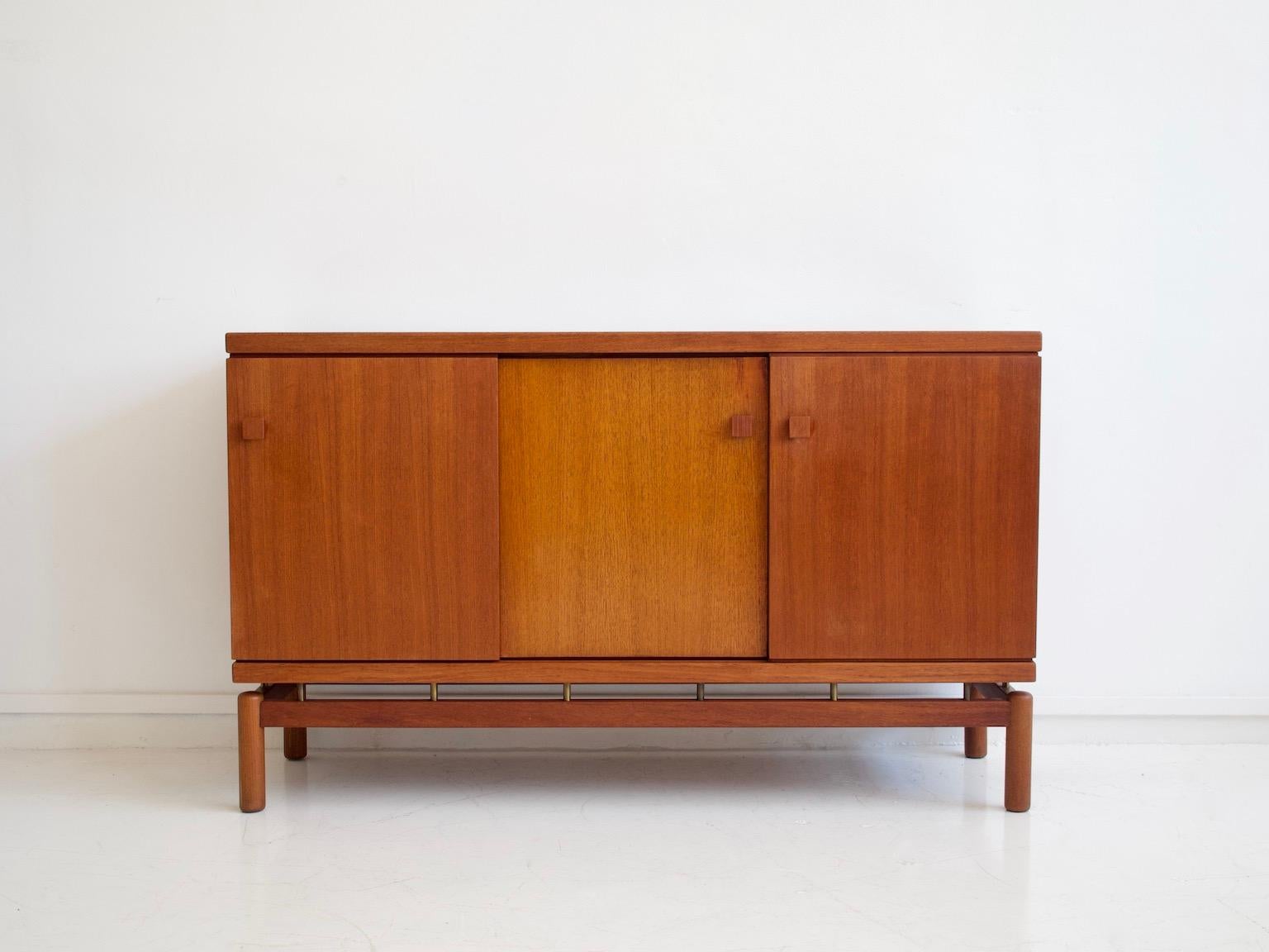 Sideboard made of teak wood with sliding doors and brass details. Manufactured and labeled by La Permanente Mobili Cantù.