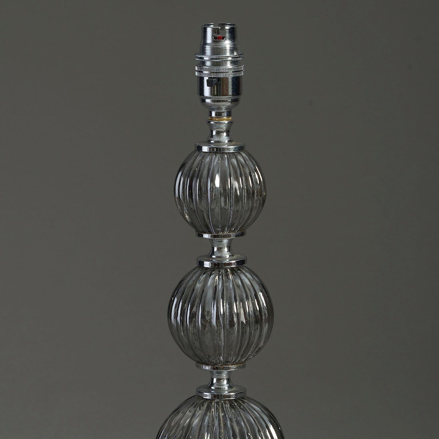A mid-twentieth century glass and chrome table lamp, the stem of three graduated ribbed spheres, mounted on a circular base.

Height dimension excludes bayonet bulb holder.

Wired to UK standards. This lamp can be rewired to all international