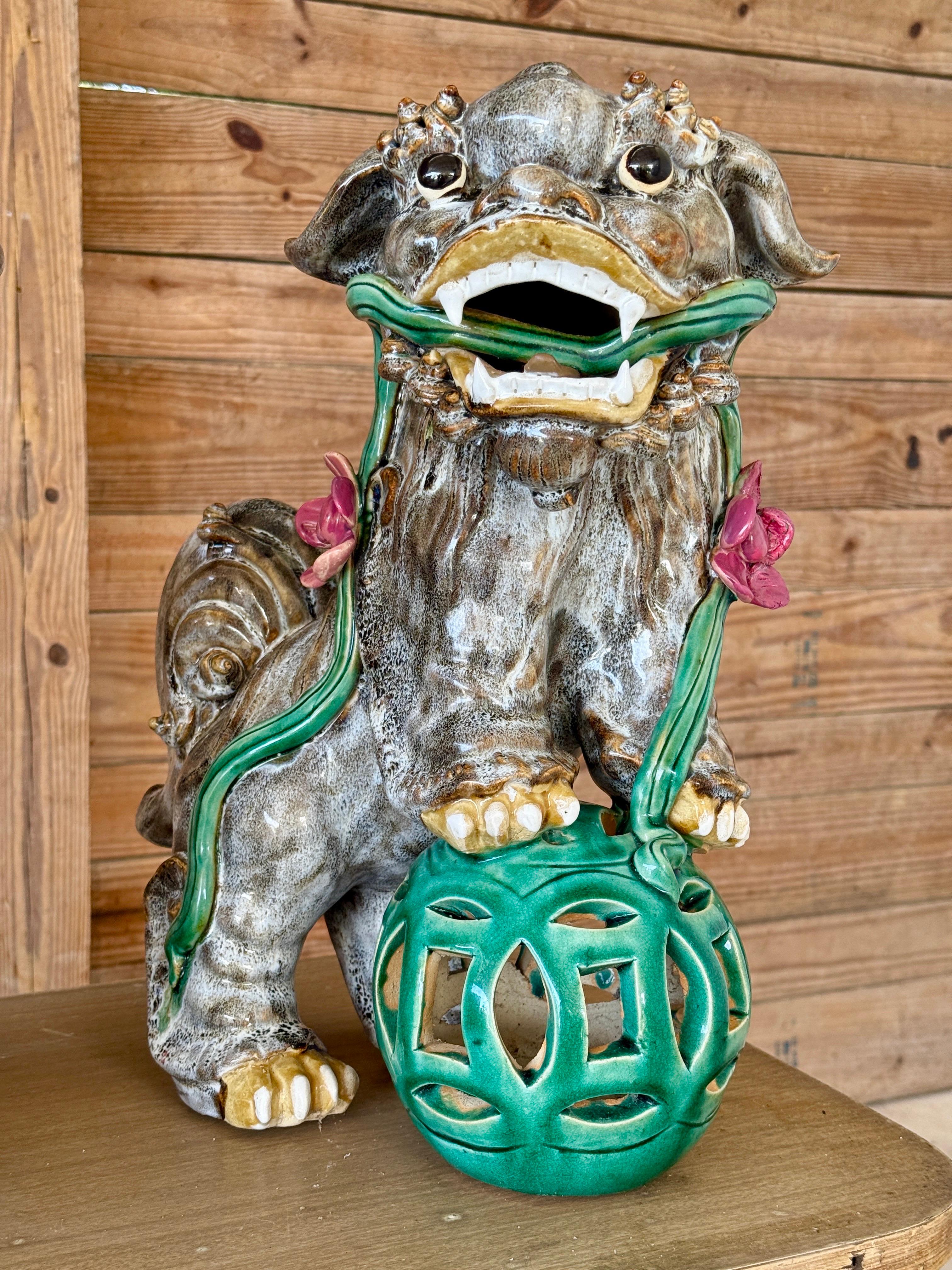 Une paire dynamique et audacieuse de chiens Foo (ou lions gardiens) en céramique émaillée du milieu du 20e siècle, à l'expression féroce, aux bouches ouvertes et aux positions puissantes, chacun posant une patte sur un orbe vert percé vibrant. Ces