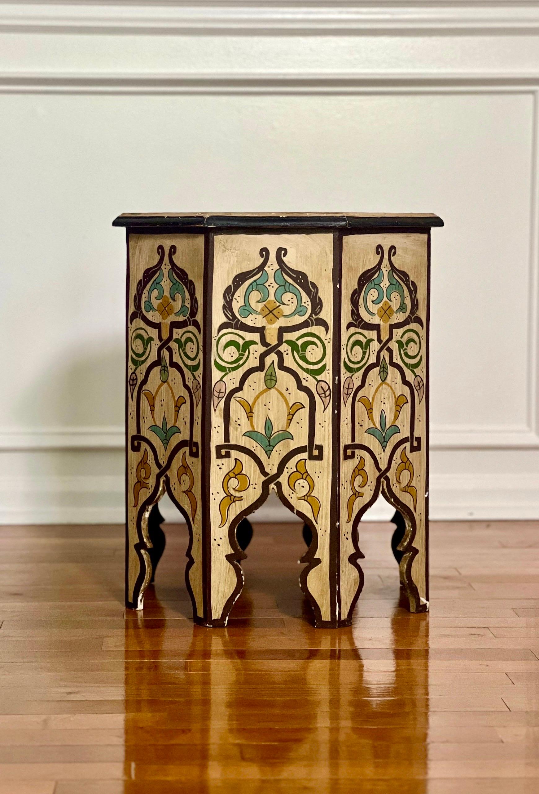 Vintage 1970s Moroccan hand-painted octagonal side table with floral and geometric designs in vibrant, earthy-toned colors. African folk art table crafted by artisans with traditional arches at the base. A nice Moorish bohemian accent to any room.