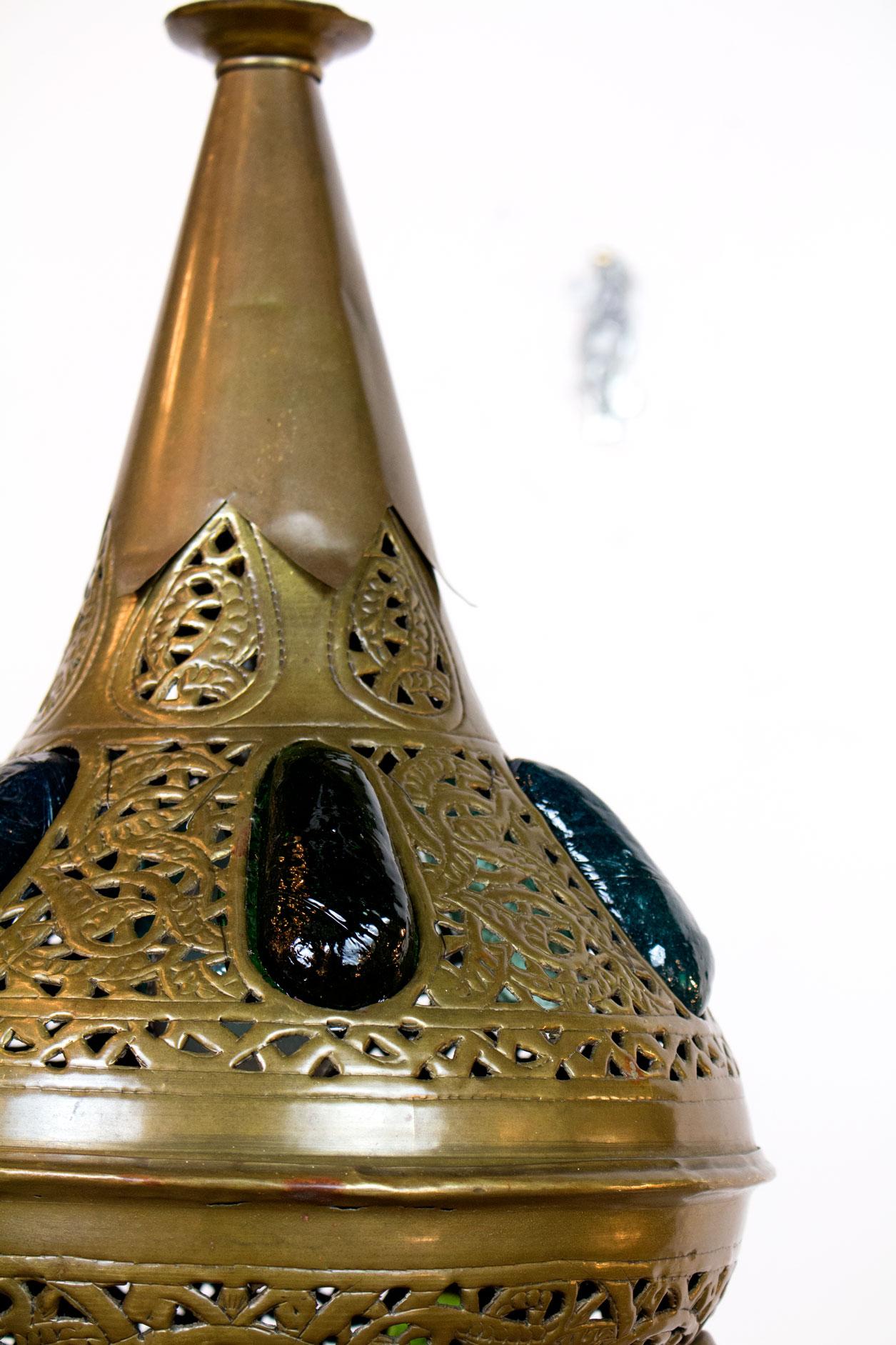 Marokkanische Pendelleuchte aus geprägtem Messing mit mehrfarbigen großen Glaseinsätzen. Glas ist ein dicker, rauer, runder Edelstein, durch den farbiges Licht scheint, wenn er beleuchtet wird. 

Abmessungen: 
Höhe: 40