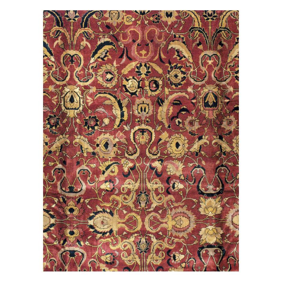 A vintage Indian Lahore large room size rug handmade during the mid-20th century with a Shah Jahan Persian Mughal style arabesque design over a marsala red field and black border.

Measures: 10'10