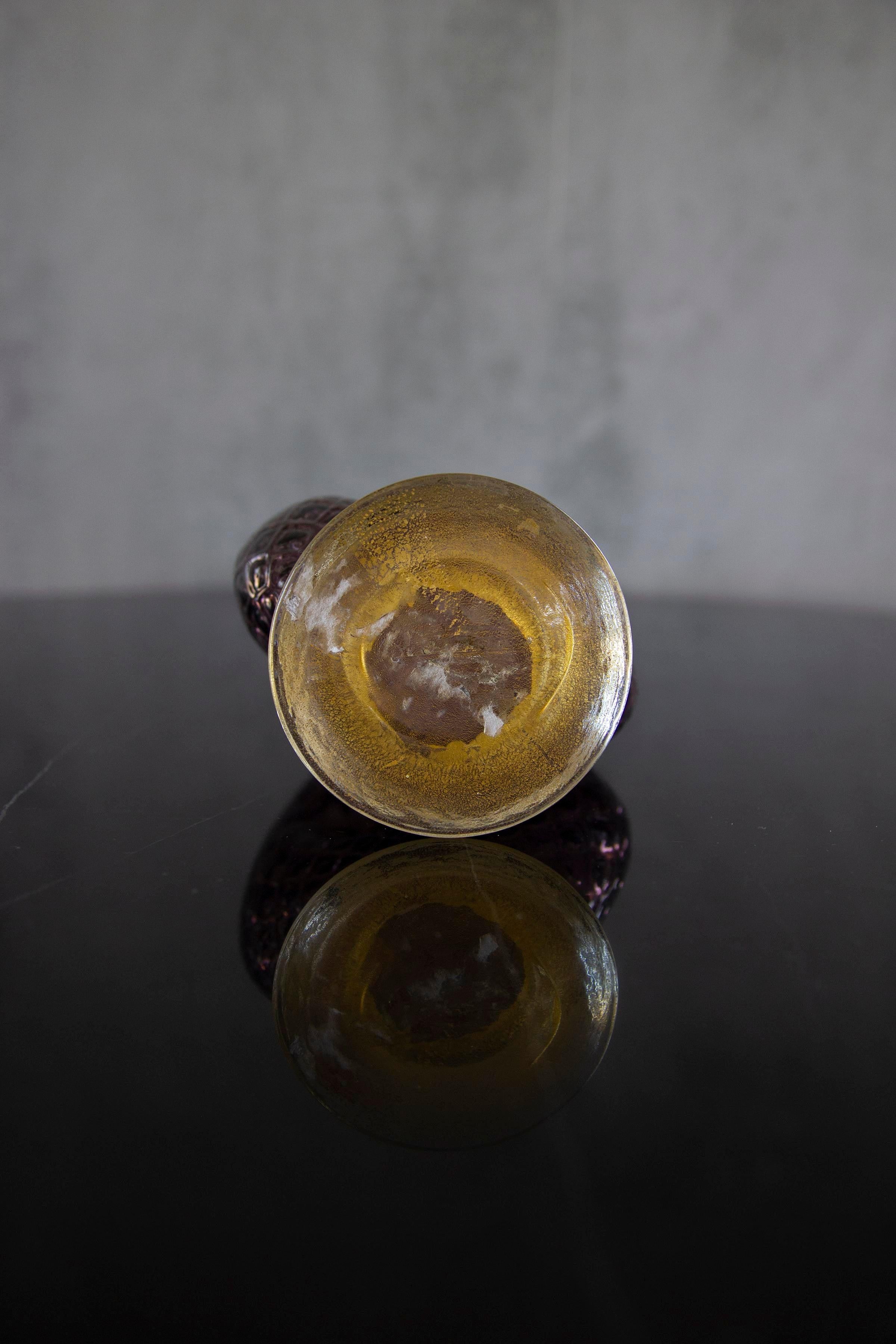 Carafe en verre de Murano composée d'un corps de couleur violette, accentué d'une basse en verre moucheté d'or, tête de lion figurative au centre. Idéal comme vase ou comme pièce unique pour votre espace de vie.