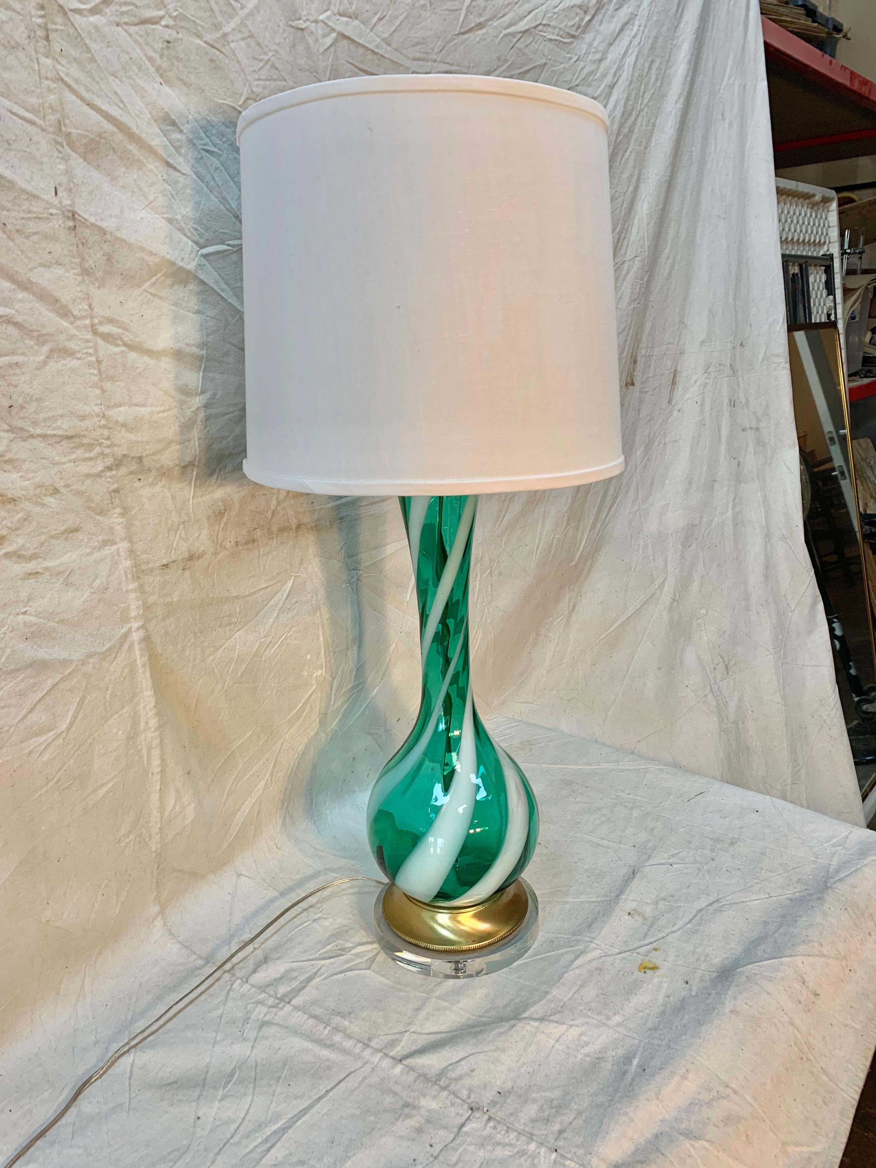 Amazing vintage 1960s Murano glass table lamp. The lamp features green and white swirl color glass with the original brass base. This lamp has been professionally rewired to USA standards with the addition of a lucite base and fitted with a new