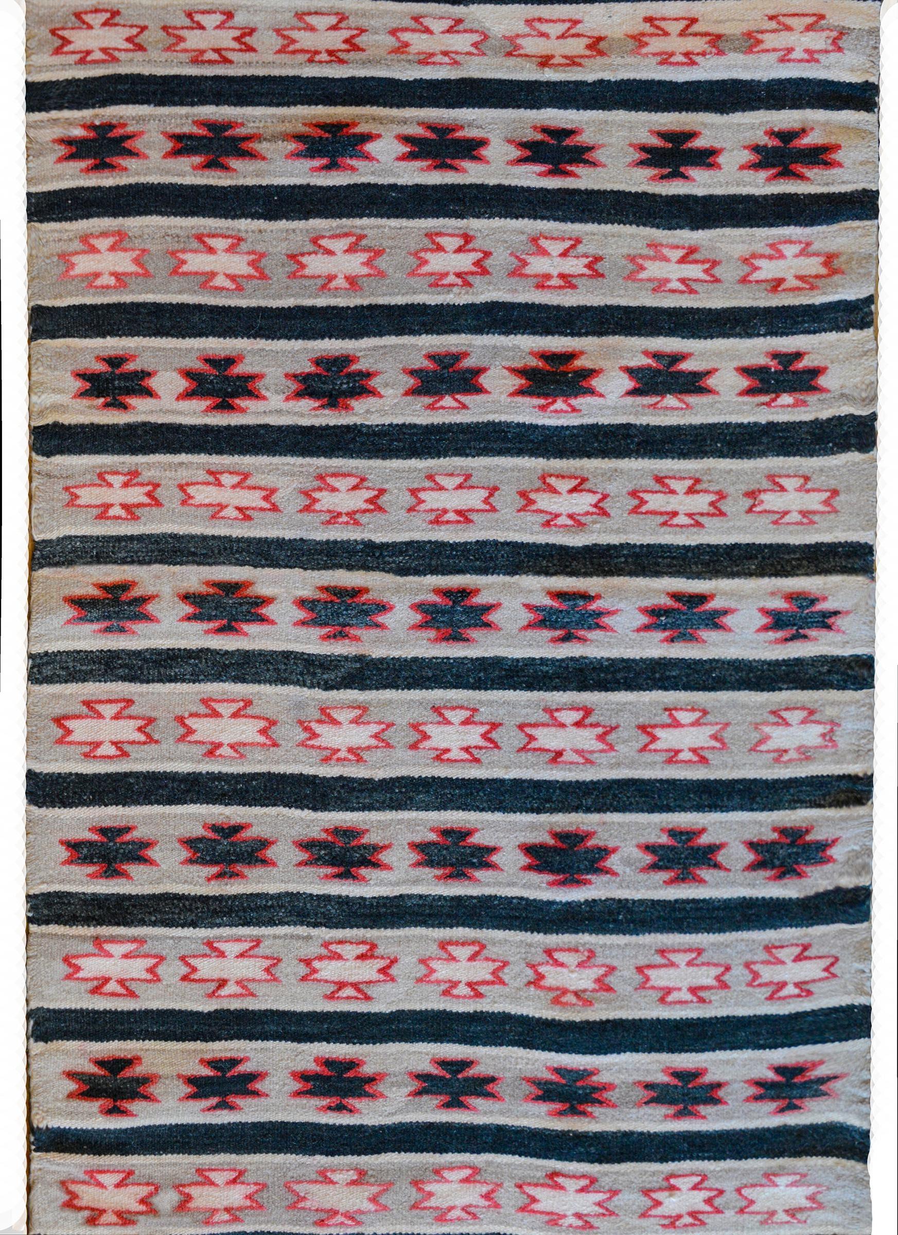 A wonderful mid-20th century Navajo rug with a bands of stars or stylized flowers alternating in crimson and black across the field.