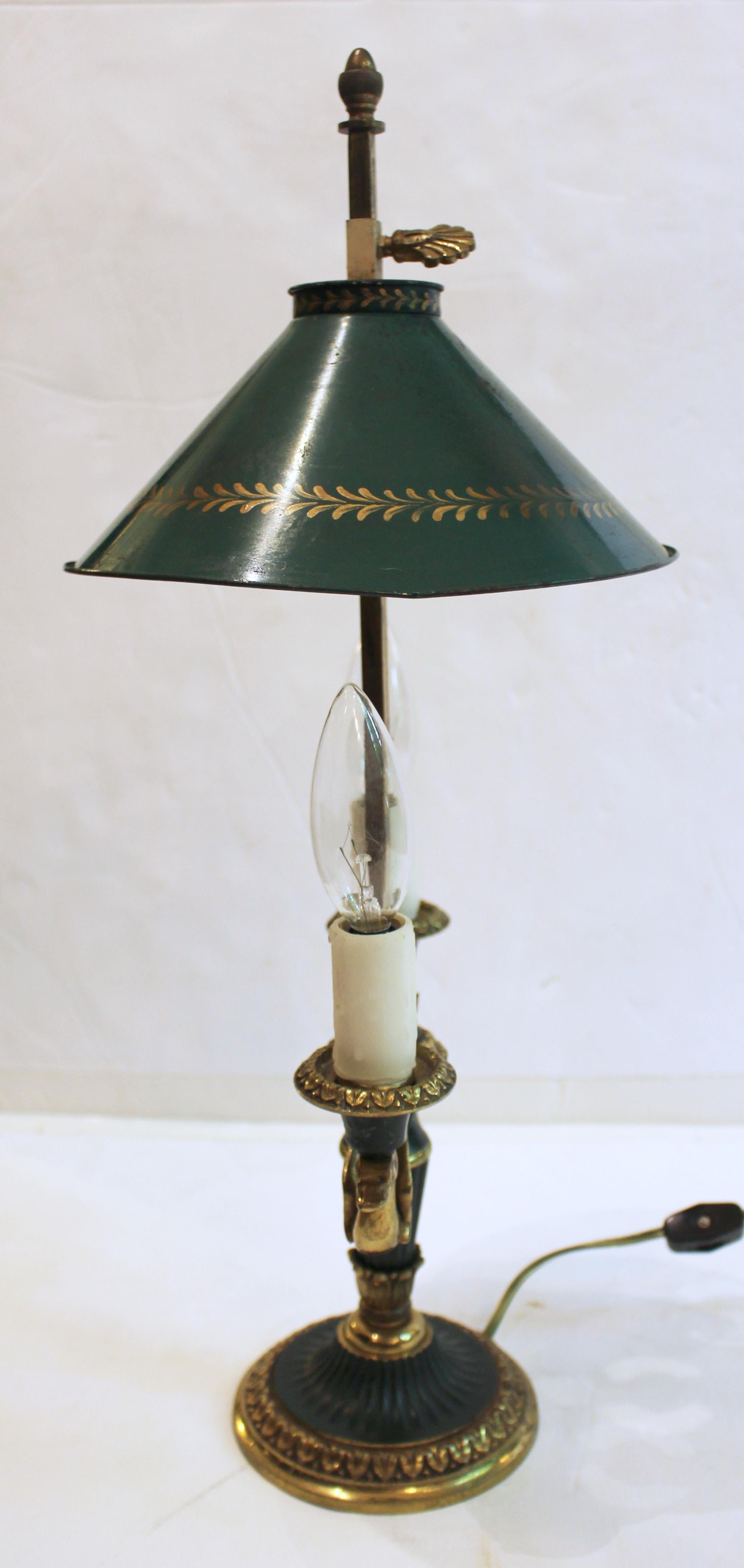 Lámpara bouillotte de bronce con motivo de cisne de mediados del siglo XX. Estilo neoclásico. Luz doble. Pintura verde y bronce dorado. Pantalla de tole verde con bordes dorados de motivos repetitivos. Pantalla de 8,25