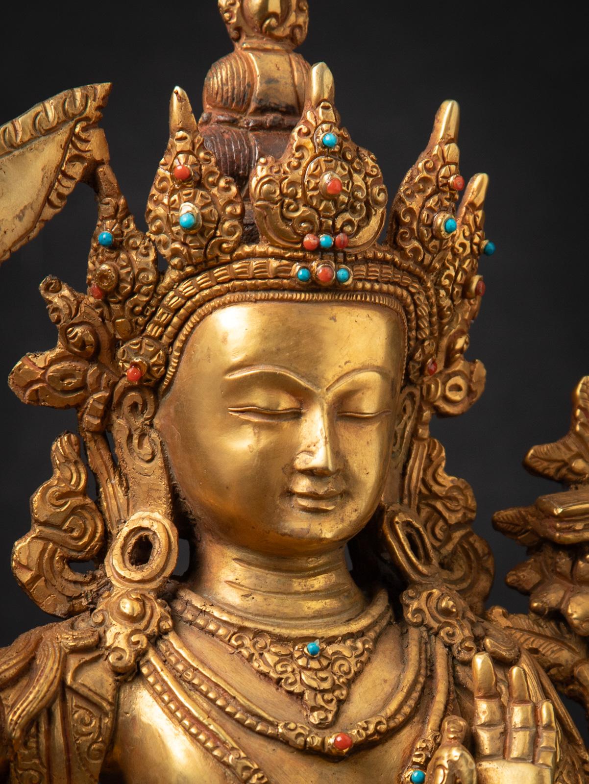 Cette statue de Manjushri en bronze ancien du Népal est une œuvre d'art captivante et complexe, magnifiquement réalisée en bronze de haute qualité et dorée à l'or fin 24 carats. D'une hauteur de 32,4 cm, d'une largeur de 24,2 cm et d'une profondeur