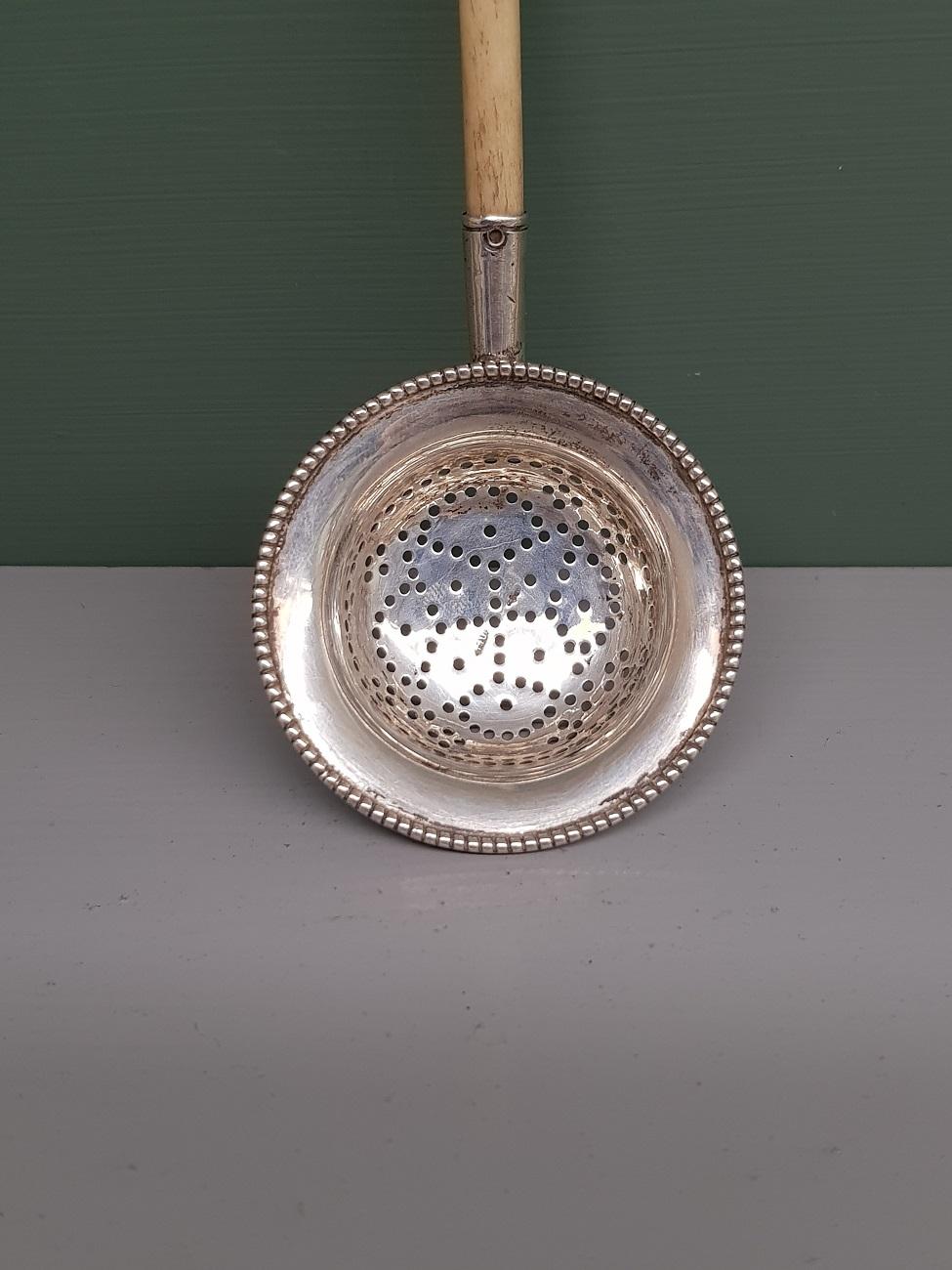Mid 20th Century Dutch silver tea strainer with bone handle and is marked with a sword and unclear maker's mark, early 20th century. 

The measurements are,
Depth 3 cm/ 1.1 inch.
Width 5.2 cm/ 2 inch.
Height 13.5 cm/ 5.3 inch.