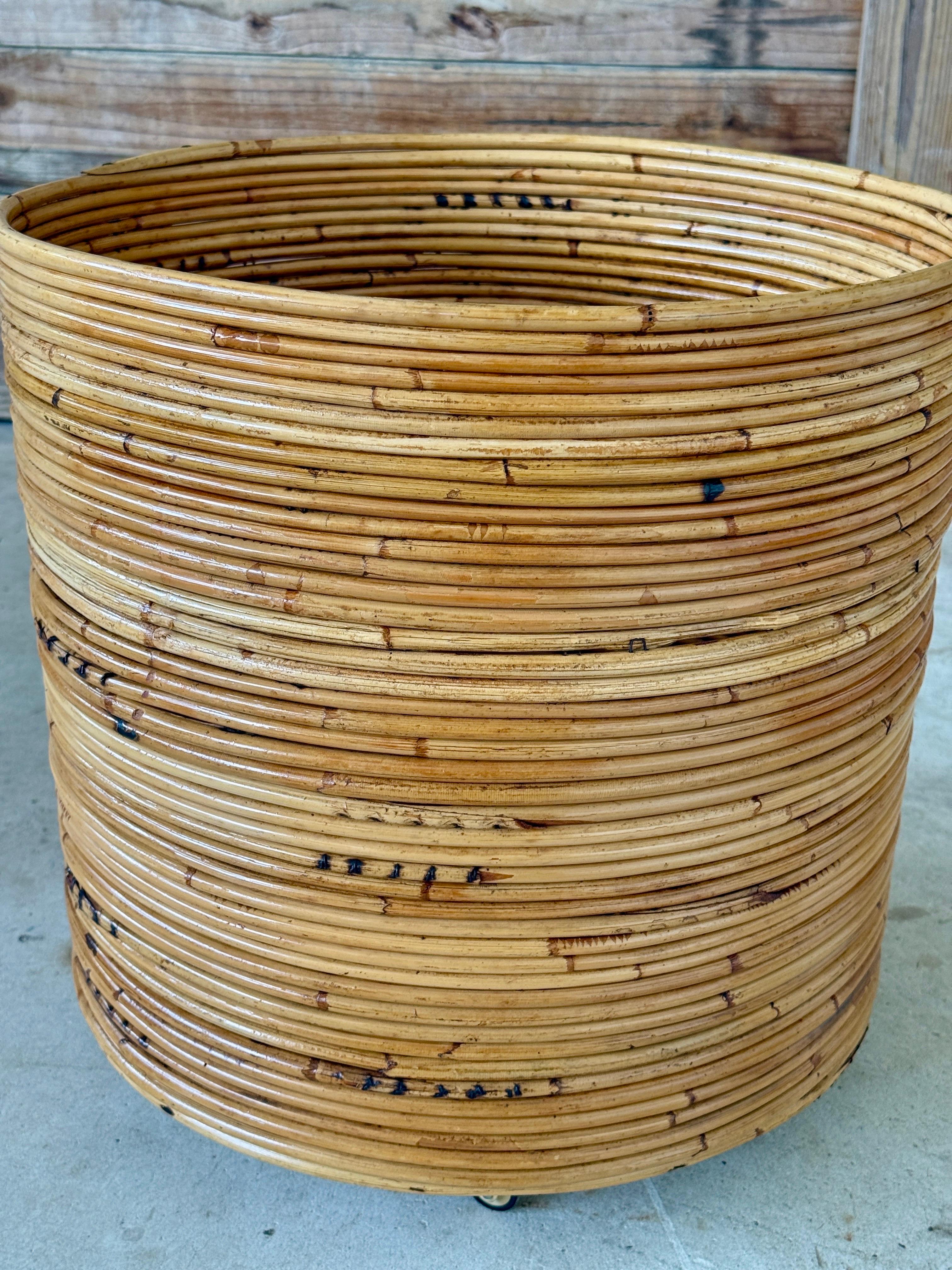 Substantial mid-20th century pencil rattan rolling piece in a bold cylindrical form. Lightly refinished to restore its warm honey tones, with a newly rebuilt base and brass wheels for function and durability. Whether used as a rolling planter or