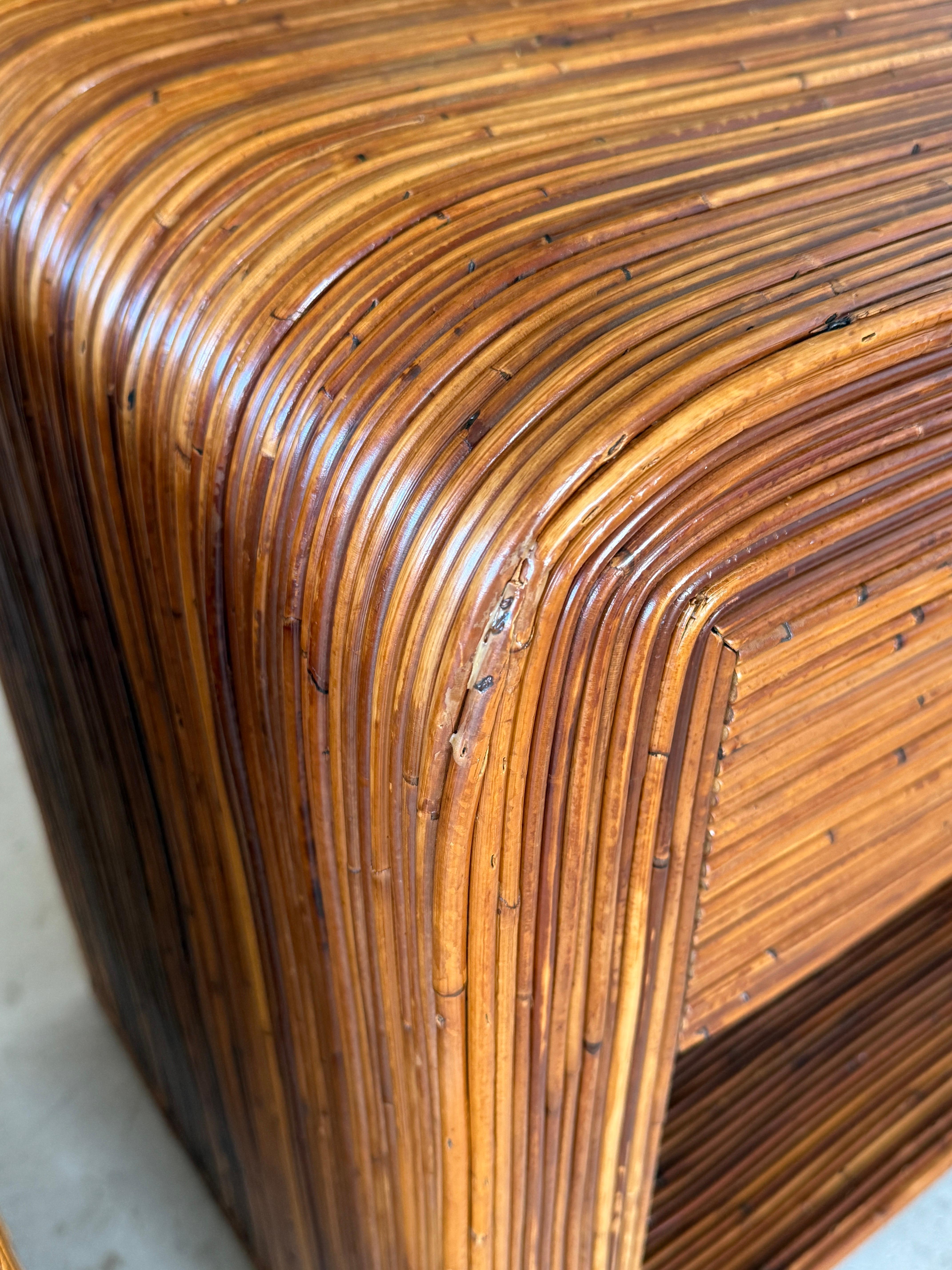 Elevate your living space with this striking pair of Mid-20th Century pencil reed rattan nightstands, meticulously refinished to showcase their stunning sculptural waterfall design. Drawing inspiration from the renowned designer Gabriella Crespi,