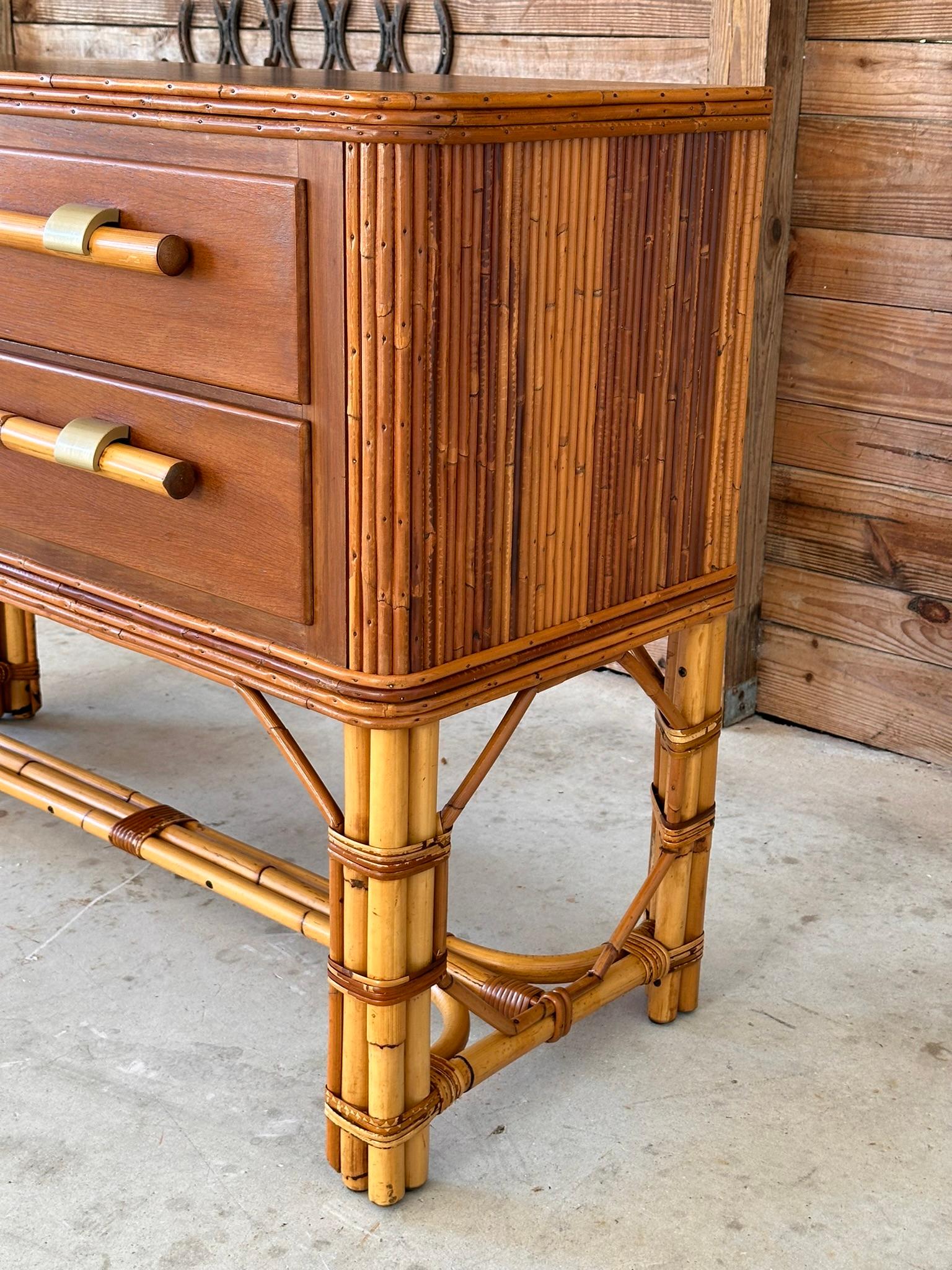 This exquisite Mid-20th Century sideboard has been meticulously refinished and restored, bringing out the natural beauty of its rattan base and pencil reed sides. The rich wood top offers a striking contrast to the intricate rattan detailing,