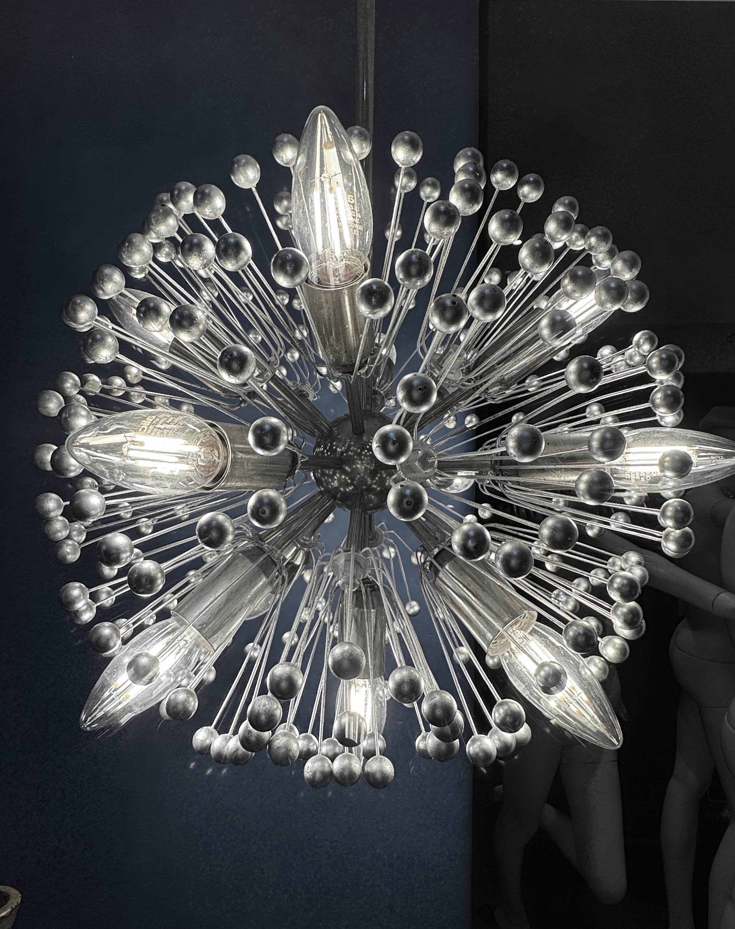 Si tratta di un lampadario Sputnik Modern di metà secolo, risalente al periodo dell'A Space Age. Presenta un nucleo centrale, spesso sferico o leggermente allungato, da cui si irradiano numerosi bracci o raggi in tutte le direzioni. Questi bracci