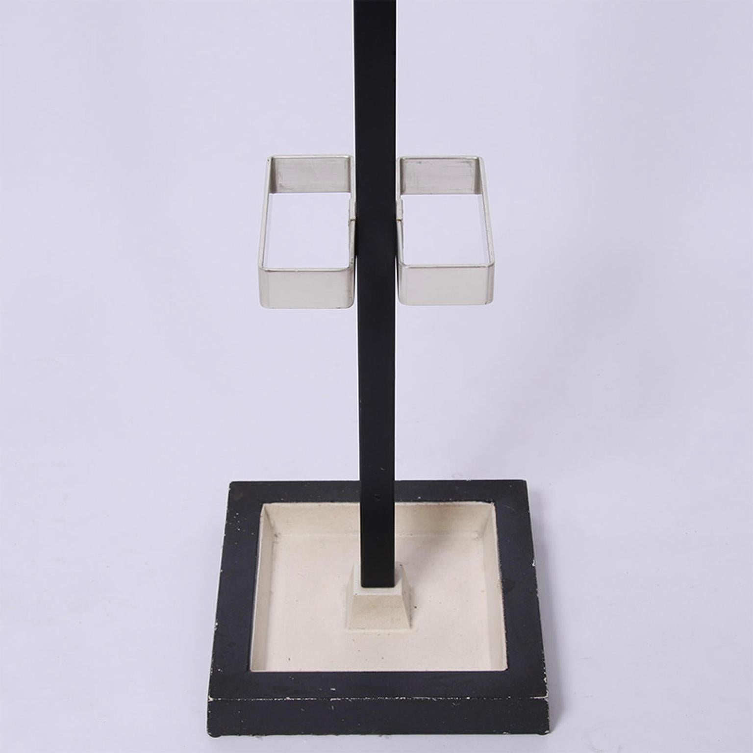 A very solid painted metal coat and umbrella stand with a black and white base and metal hooks.