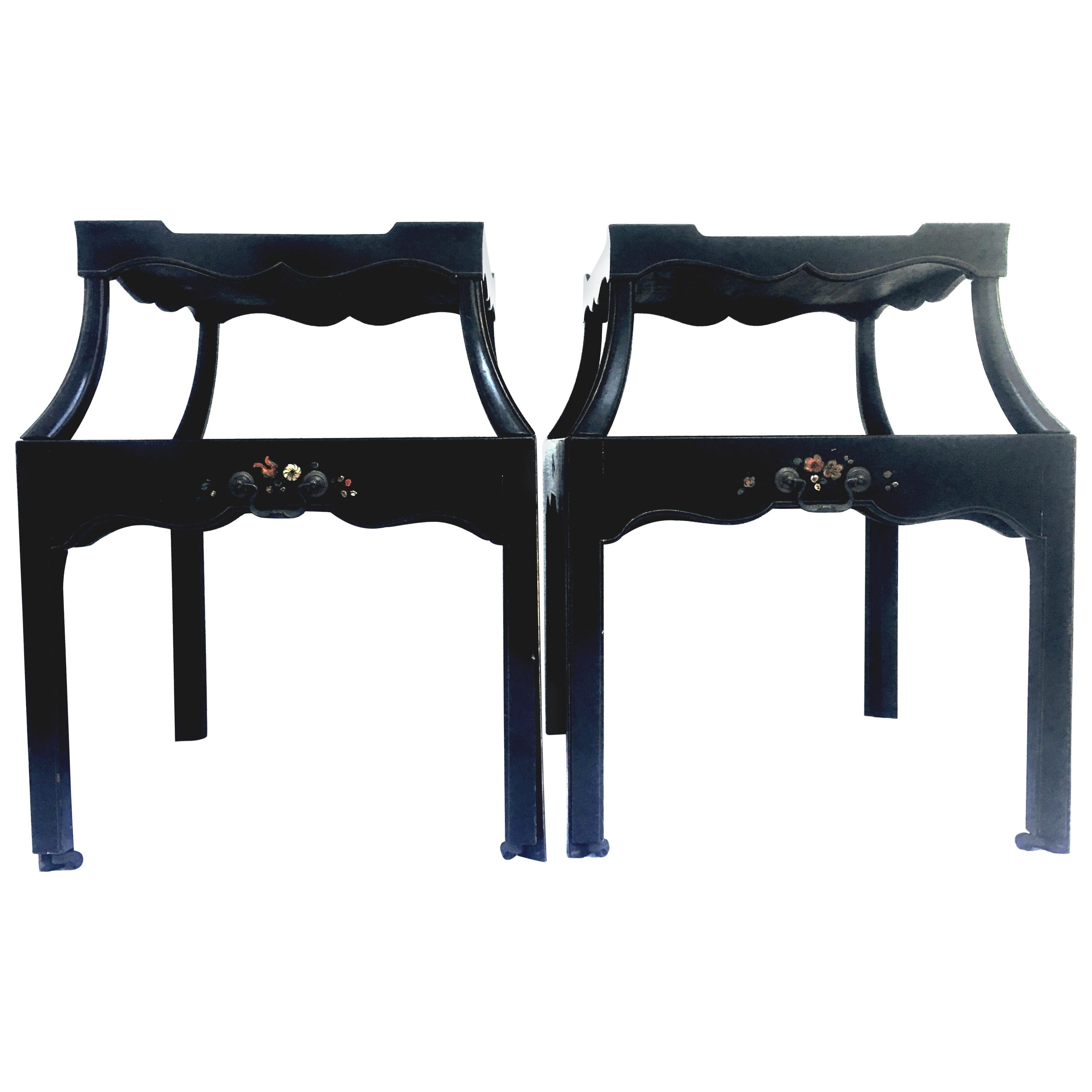 Mid-20th century pair of ebonized wood hand painted two-tier rolling side tables. These finely crafted and unique tables feature a mahogany black ebonized finished with hand painted floral motif and gilt gold brass inlay detail. Each table has a