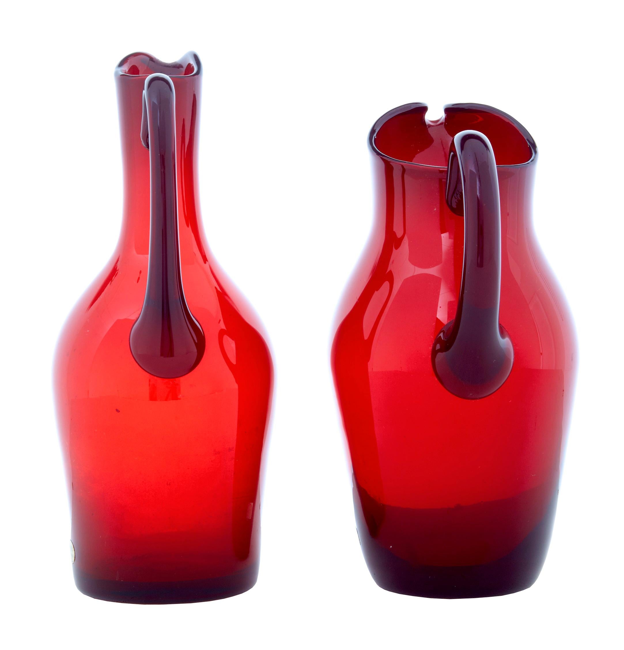 Mid 20th century pair of 1950's red art glass jugs by Monica Bratt circa 1950.

Monica Bratt (1913-1961) was a Swedish artist who worked mainly in glassware at the Reijmyre glassworks.

Stunning pair of claret or water jugs, ideal for display or