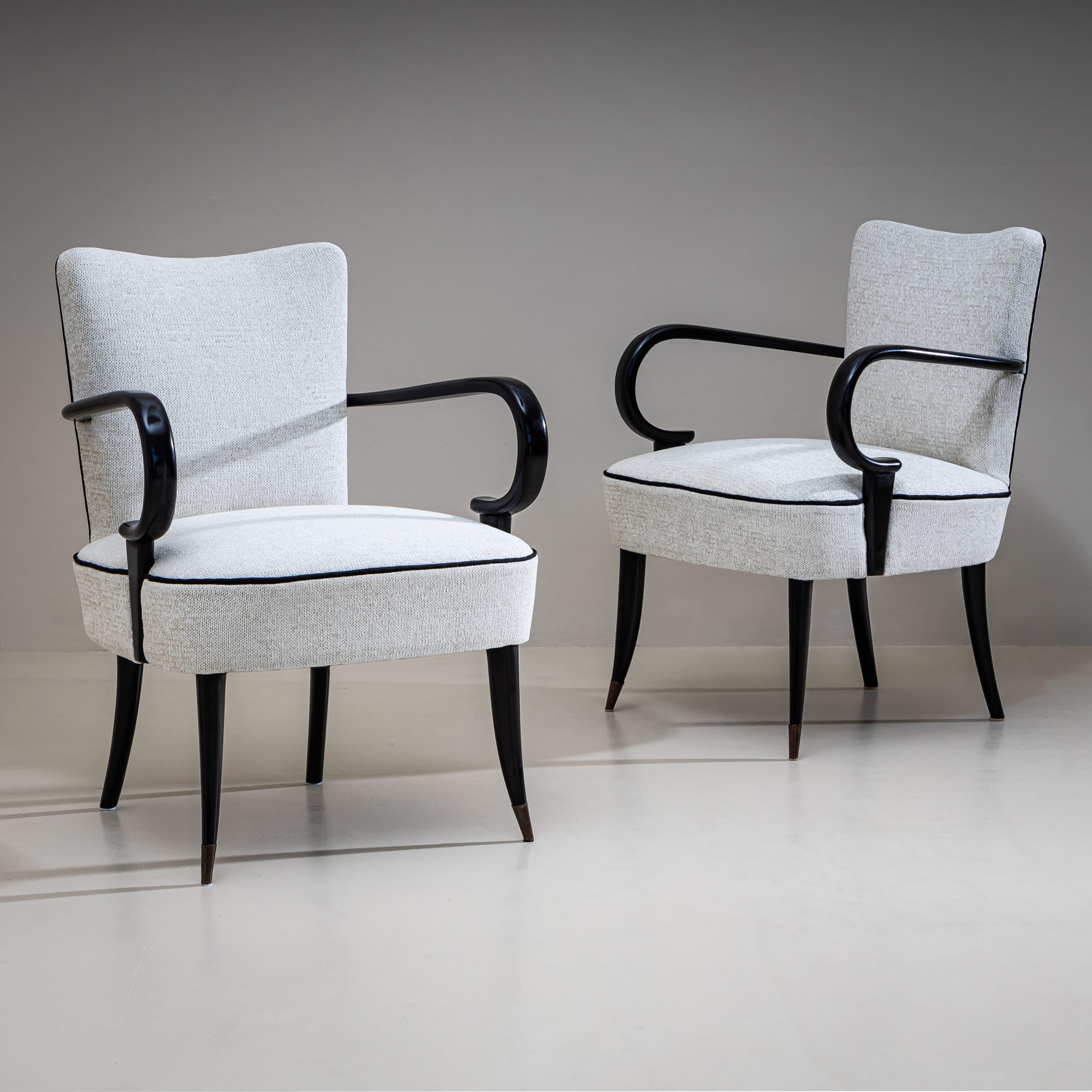 Paire de fauteuils aux accoudoirs arrondis et ébonisés et aux assises et dossiers rembourrés. Les chaises ont été récemment retapissées dans un tissu gris clair.