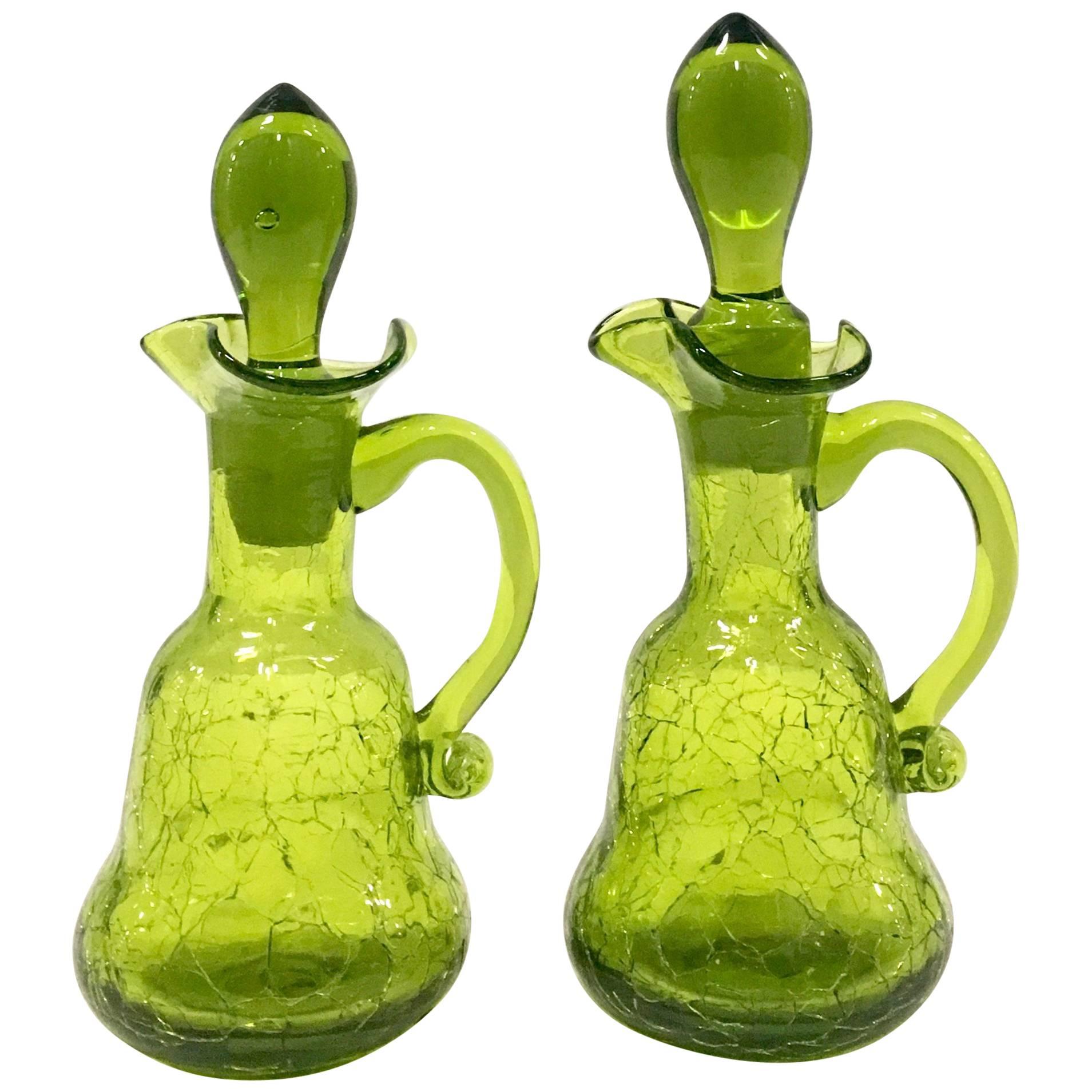 Mid-20th century pair of Blenko style blown crackle glass, olive green cruet decanters. Features applied curved handles, ruffle neck detail and 