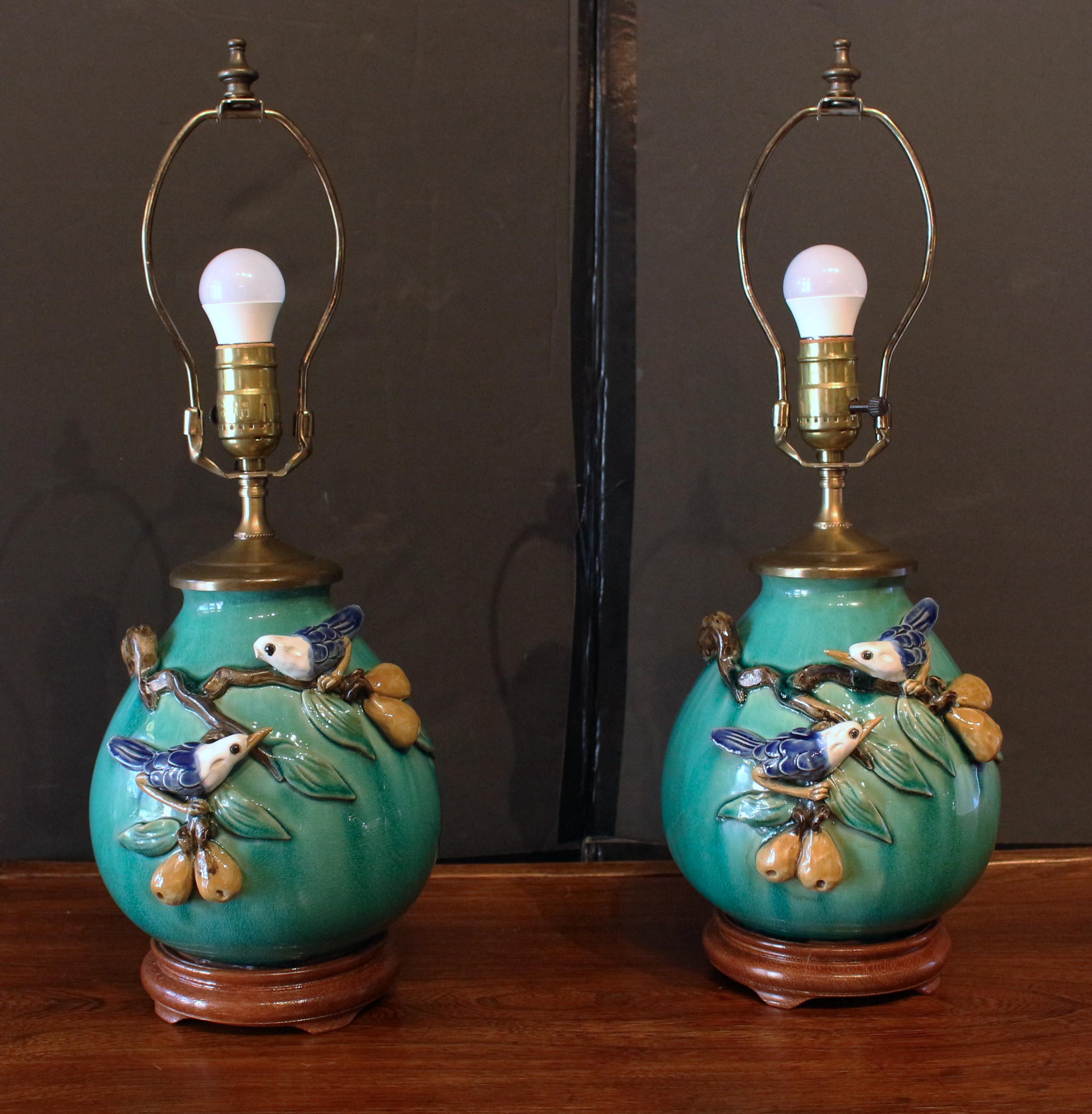 Pair of Chinese porcelain jars, now lamps, mid-20th century. Wood bases & brass caps. Each with birds on pear tree branches laden with fruit. One bird lacks beak. 14.25