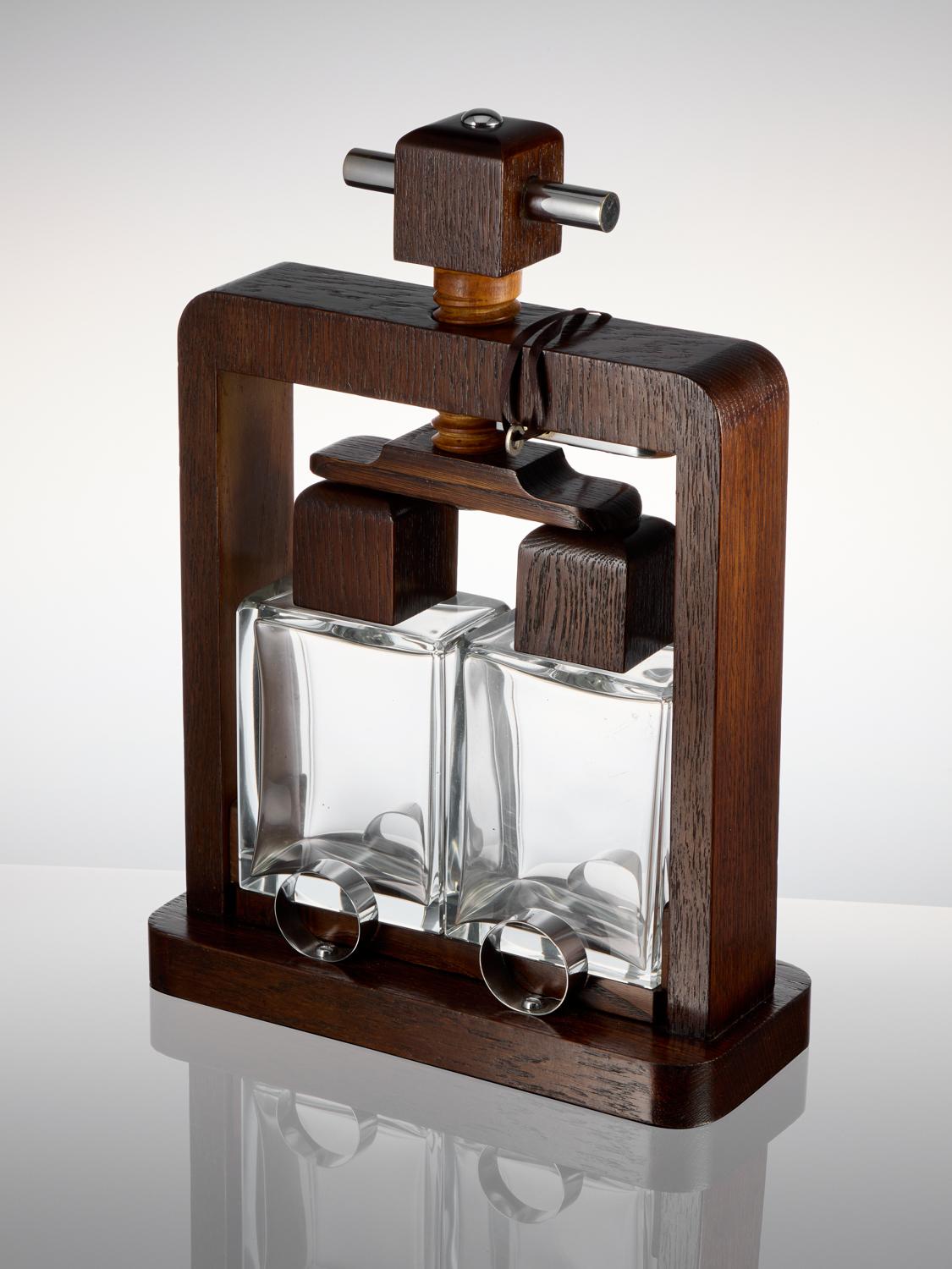 Presenting a rare and impressive Art Deco pair of mounted decanters in a tantalus from France, dating back to circa 1930.

This unique drinks tantalus features a pair of decanters elegantly mounted within a press-like structure. By turning the