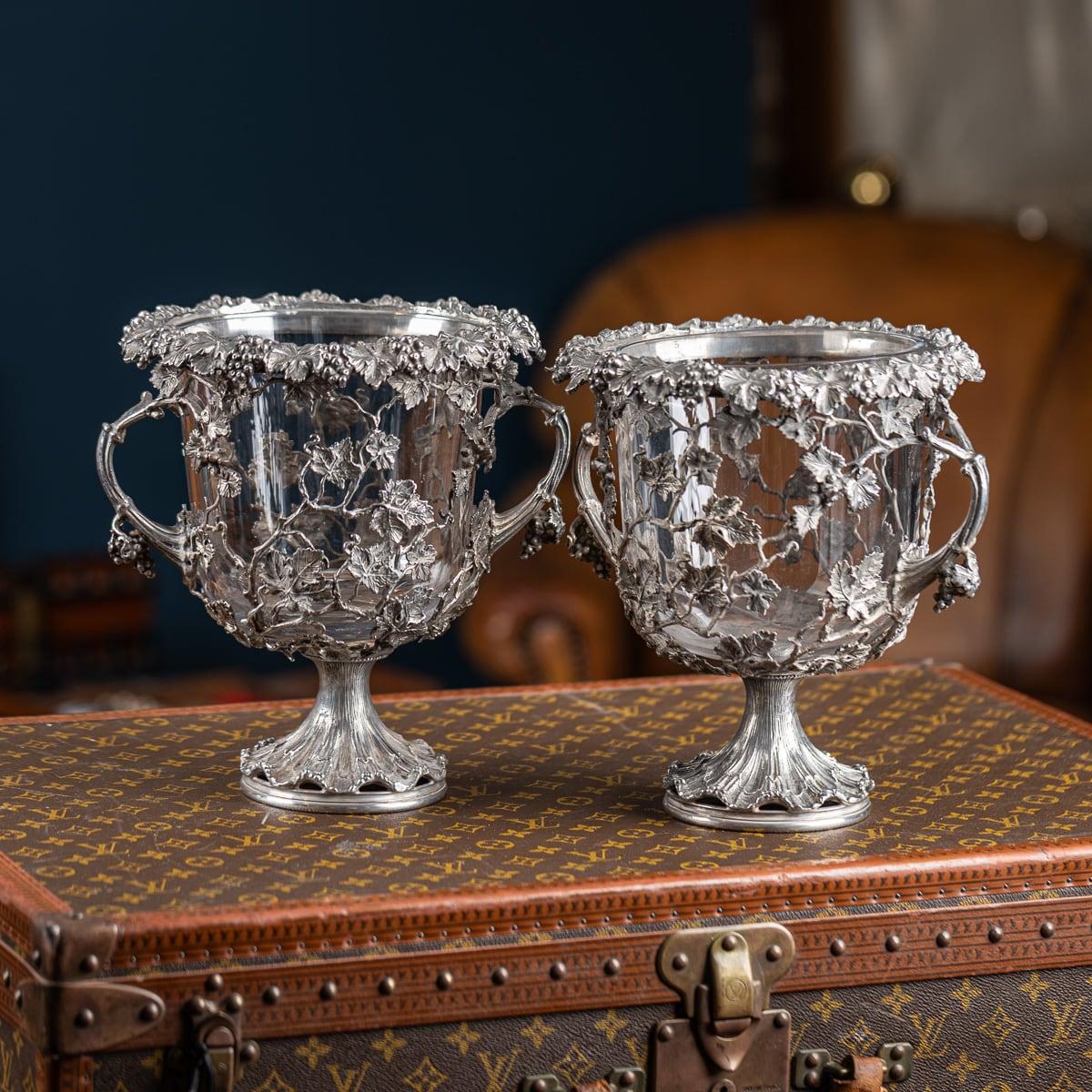 Pareja de enfriadores de vino de plata maciza de mediados del siglo XX con inserciones de cristal transparente. Con decoración de vides fundidas, racimos y follaje a lo largo de los bordes. El cuerpo ornamentado y perforado, provisto de pesadas